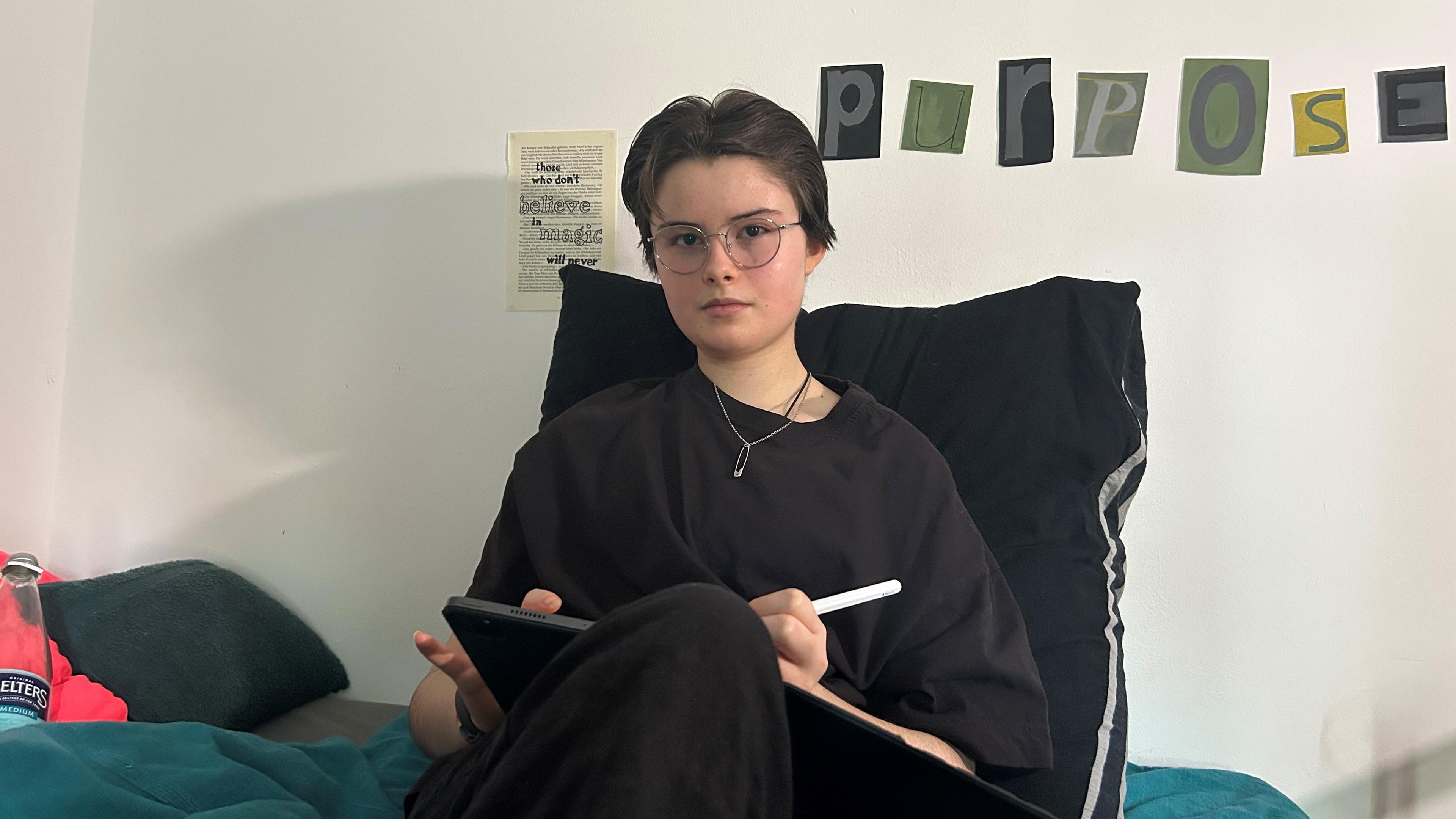 13歳のロリは、タブレットと一緒にベッドに座っています。ロリには、筋ジ症の脳脊髄炎/慢性疲労症候群（ME/CFS）があります。