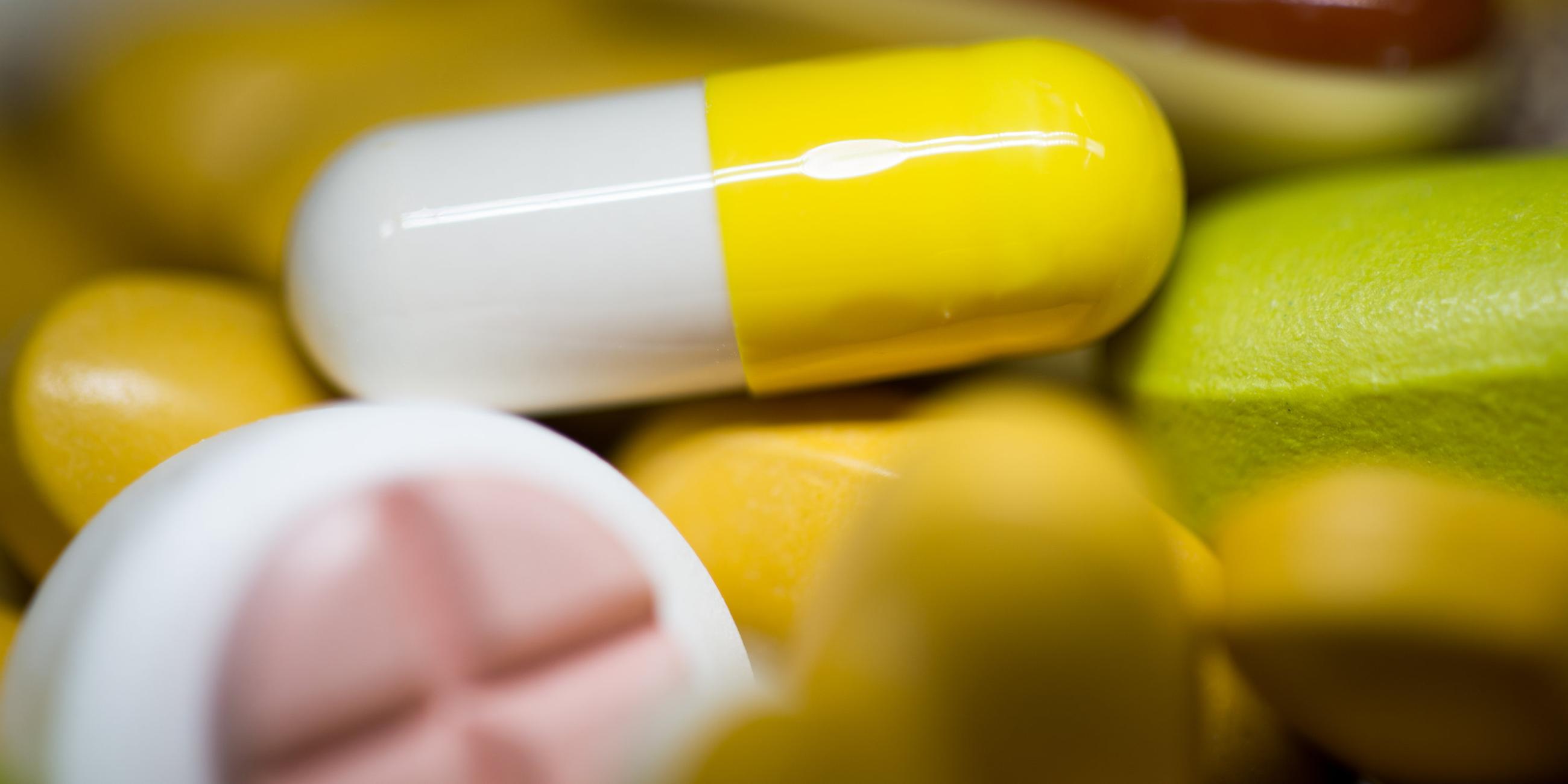 Tabletten, kKapseln und Pillen in verschiedenen Farben liegen in einem Medikamenten-Behälter einer Apotheke.