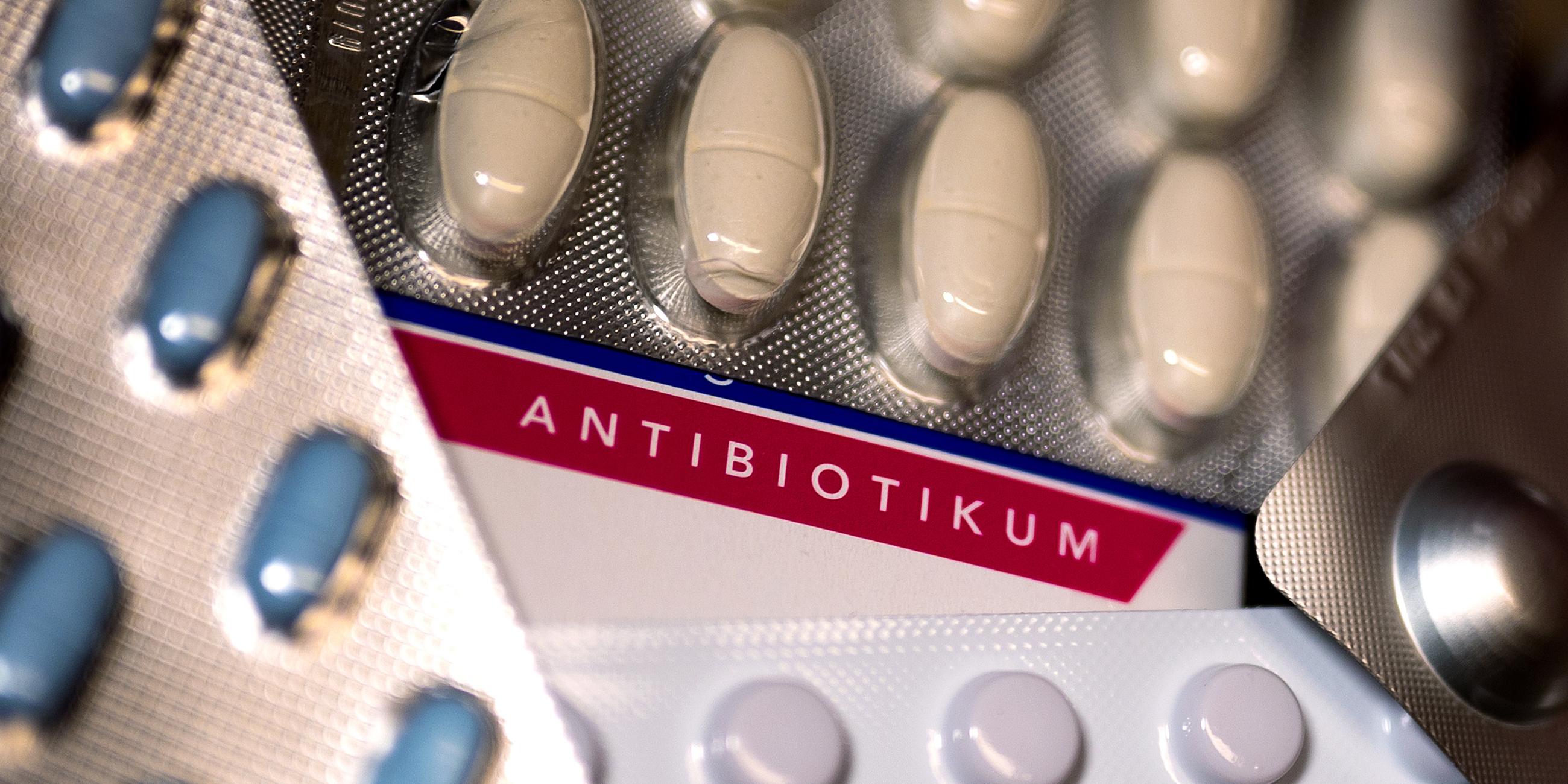 Mehrere Blister mit Tabletten und Pillen überdecken eine Packung mit der Aufschrift "Antibiotikum".