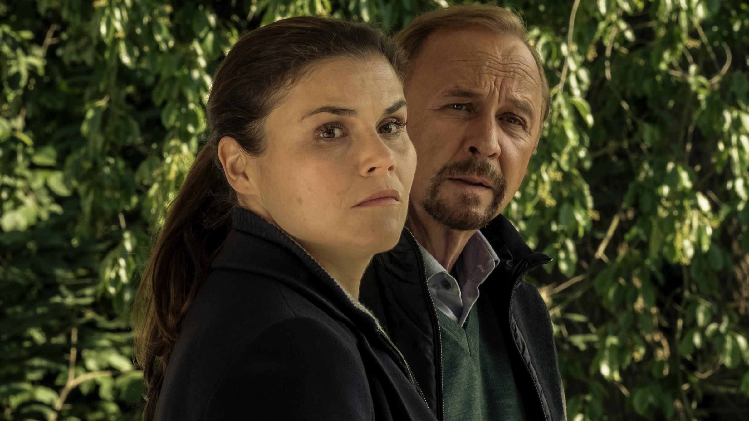 Nina Petersen (Katharina Wackernagel) und Karl Hidde (Alexander Held) stehen vor einer großen Hecke.