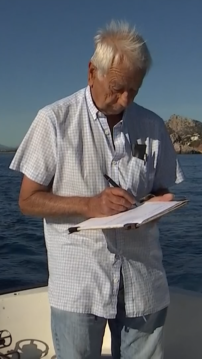 Ein älterer Mann auf einem Boot, der etwas notiert.