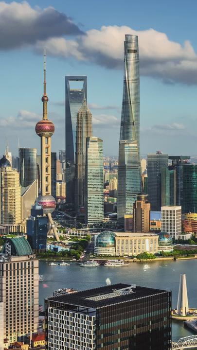 "Meilensteine der Technik: Aufzüge": Skyline Shanghai mit vielen Hochhäusern, ein Fluss schlängelt sich durch die Betonbauten der dichtbebauten Stadt.
