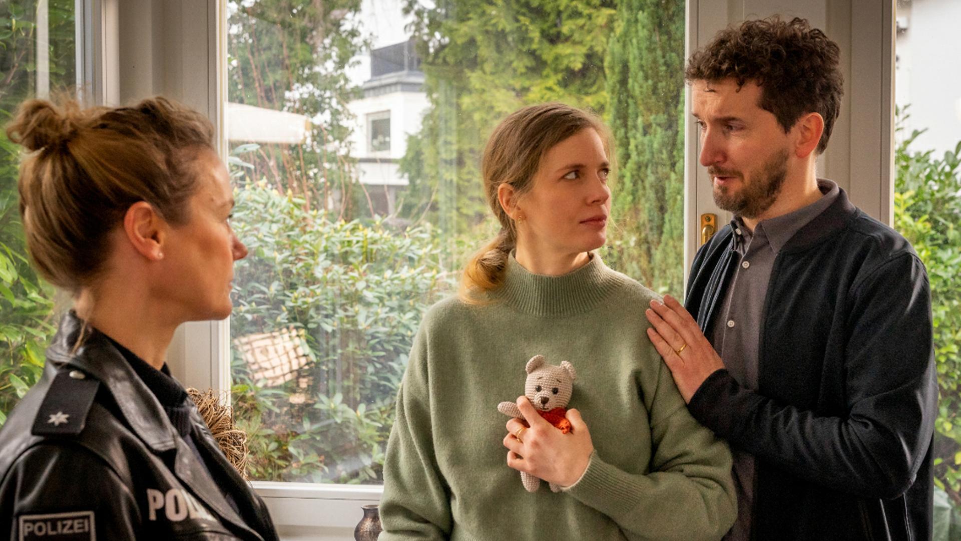 Steffi hält in ihrer linken Hand einen gehäkelten Teddybären, den sie an ihren Oberkörper drückt.