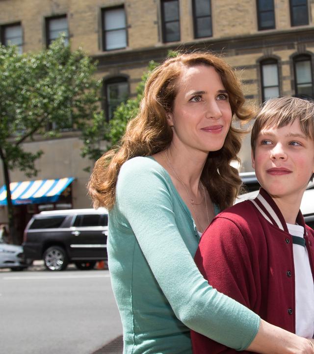 "Katie Fforde: Mein Sohn und seine Väter": Karen Wood (Julia Malik) umarmt ihren Sohn Luke (Finn Fiebig) innig auf einer Straße in Brooklyn.