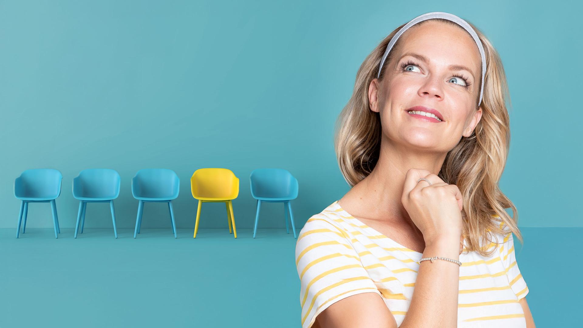 Eva Brenner schaut gedankenverloren nach oben links. Rechts im Hintergrund die Animation einer blau-gelben Stuhlreihe.