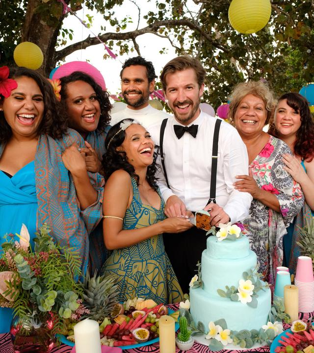 Mit dem Brautpaar Lauren (Miranda Tapsell, 3.v.l.) und Ned (Gwilym Lee, M.) freuen sich die Hochzeitsgäste: Neds Bruder Robbie (Matt Crook, l.), die Brautjungfern Dana (Elaine Crombie, l.), Kailah (Dalara Williams; 2.v.l.) und Ronelle (Shari Sebbens, r.), der Pfarrer (Rob Collins, Mitte hinten), Cousin Braydon (Shaka Cook, r.) und Tante Bree (Tessa Rose, 2.v.r.).