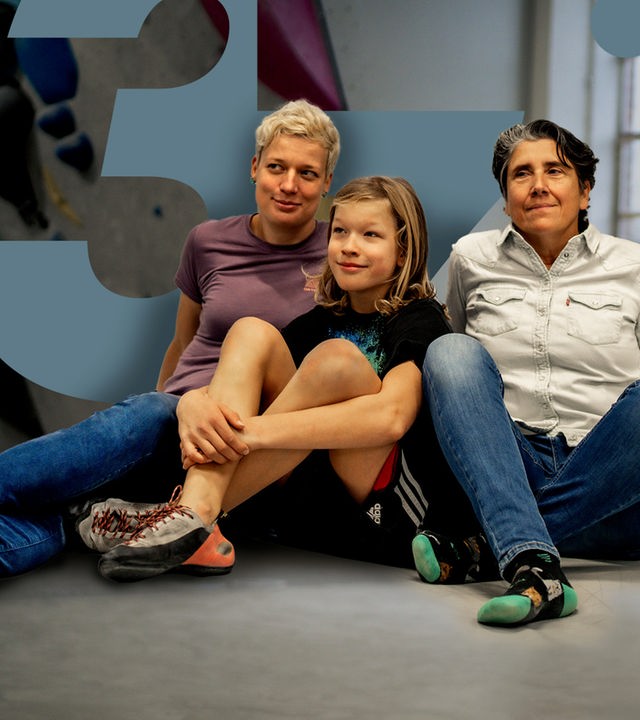 In der Boulderhalle sitzen Judith, Oskar und Andrea zusammen auf dem Boden. Ihr gemeinsamer Sohn Oskar sitzt in der Mitte.