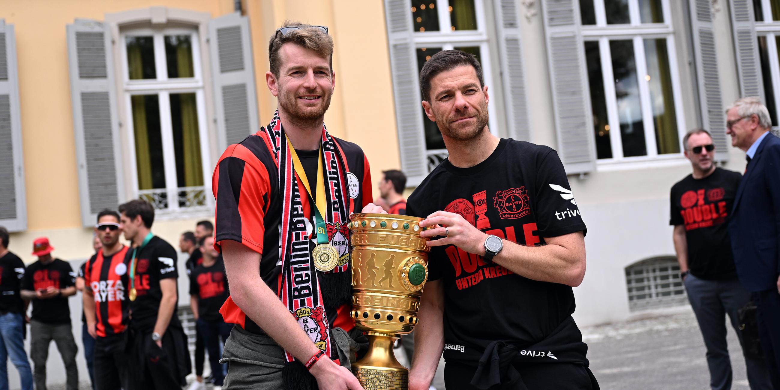 Leverkusens Torhüter Lukas Hradecky (l) und Leverkusens Trainer Xabi Alonso kommen mit dem Pokal zum Schloss Morsbroich, um sich in das Goldene Buch der Stadt einzutragen. 