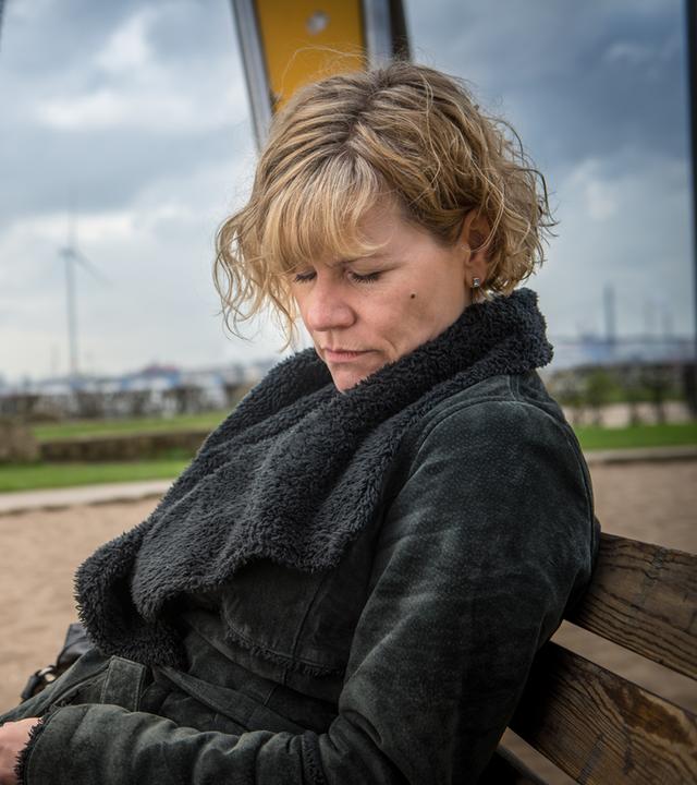 "Notruf Hafenkante - Melody": Im Vordergrund sitzt Karin Berger (Anne Kasprik) schlafend auf einer Parkbank. Im Hintergrund schaukelt die fünfjährige Antonia (Neala Hoppe) auf einer Spielplatzschaukel.