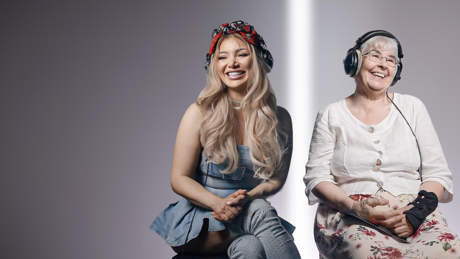 Eine junge und eine alte Frau sitzen nebeneinander und lachen. Sie tragen Kopfhörer.