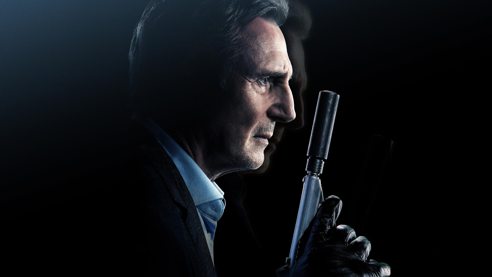 Liam Neeson hält eine Waffe mit Schalldämpfer in der behandschuhten Hand.