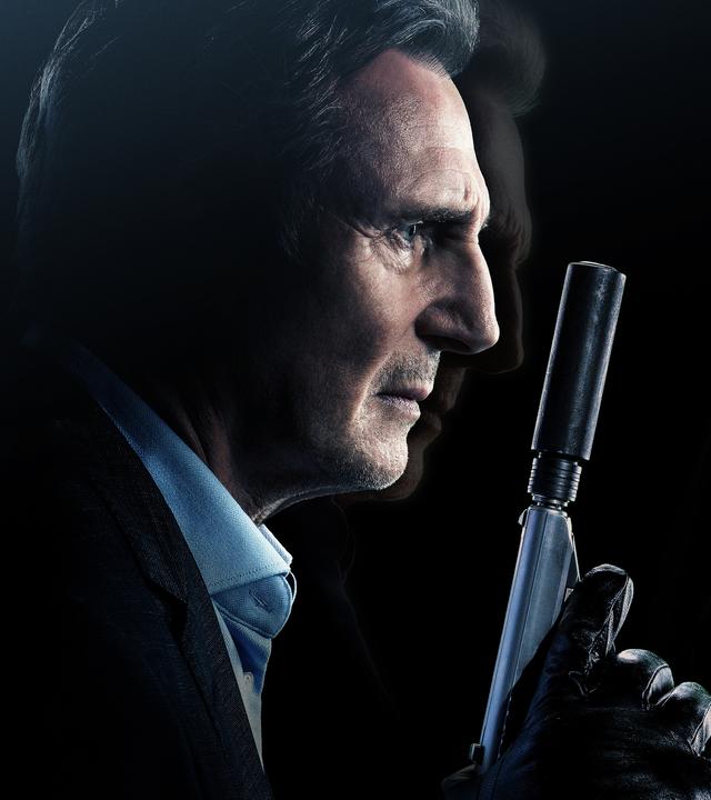 Liam Neeson hält eine Waffe mit Schalldämpfer in der behandschuhten Hand.