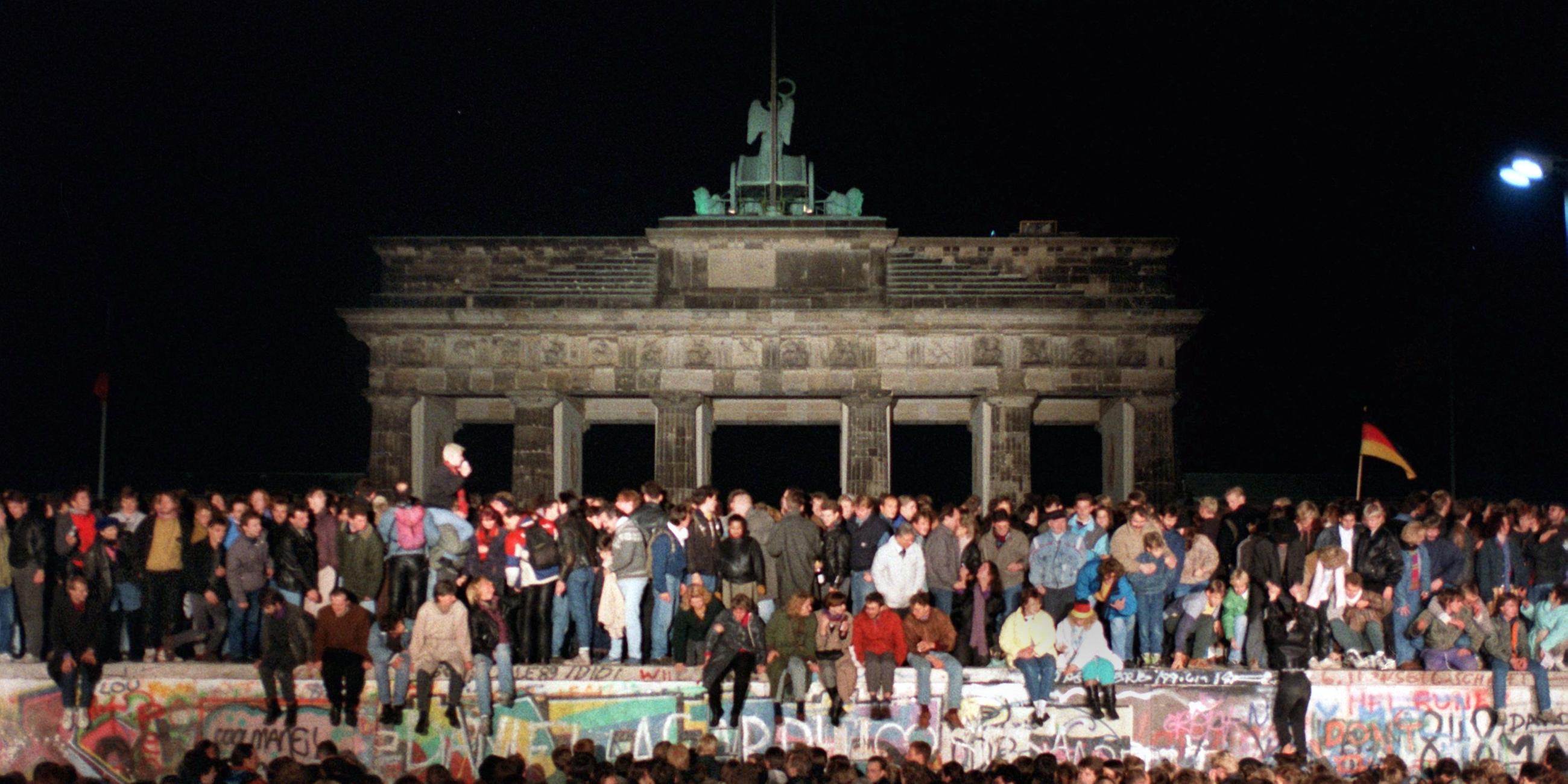 Menschen feiern den Mauerfall vor dem Brandenburger Tor in Berlin 1989