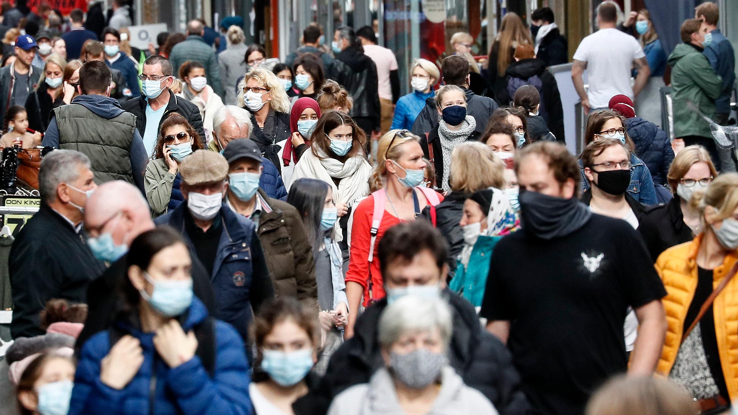 Menschen mit Masken in einer Fußgängerzone 