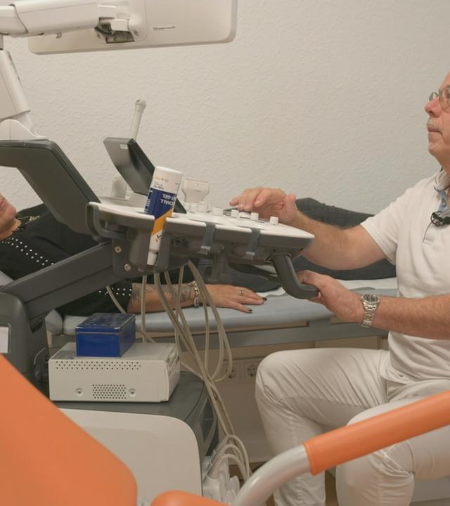 Frau auf Liege Arzt schaut auf Bildschirm