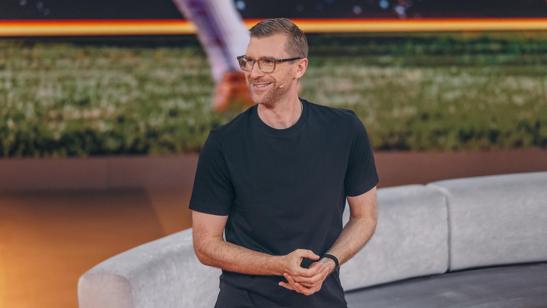 Per Mertesacker steht mit einem schwarzen T-Shirt im ZDF-WM-Studio und blickt lächelnd nach links.