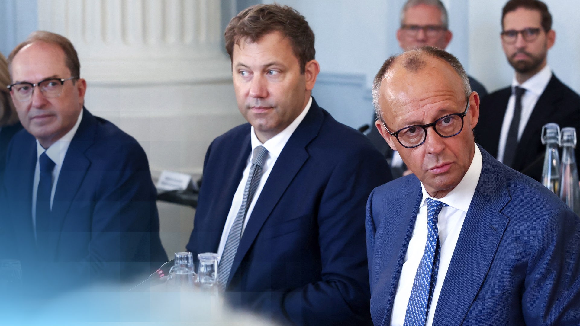 Friedrich Merz, Lars Klingbeil und Alexander Dobrindt sitzen beim gemeinsamen Foto vor der Kabinettsklausur nebeneinander und schauen in die Kameras.
