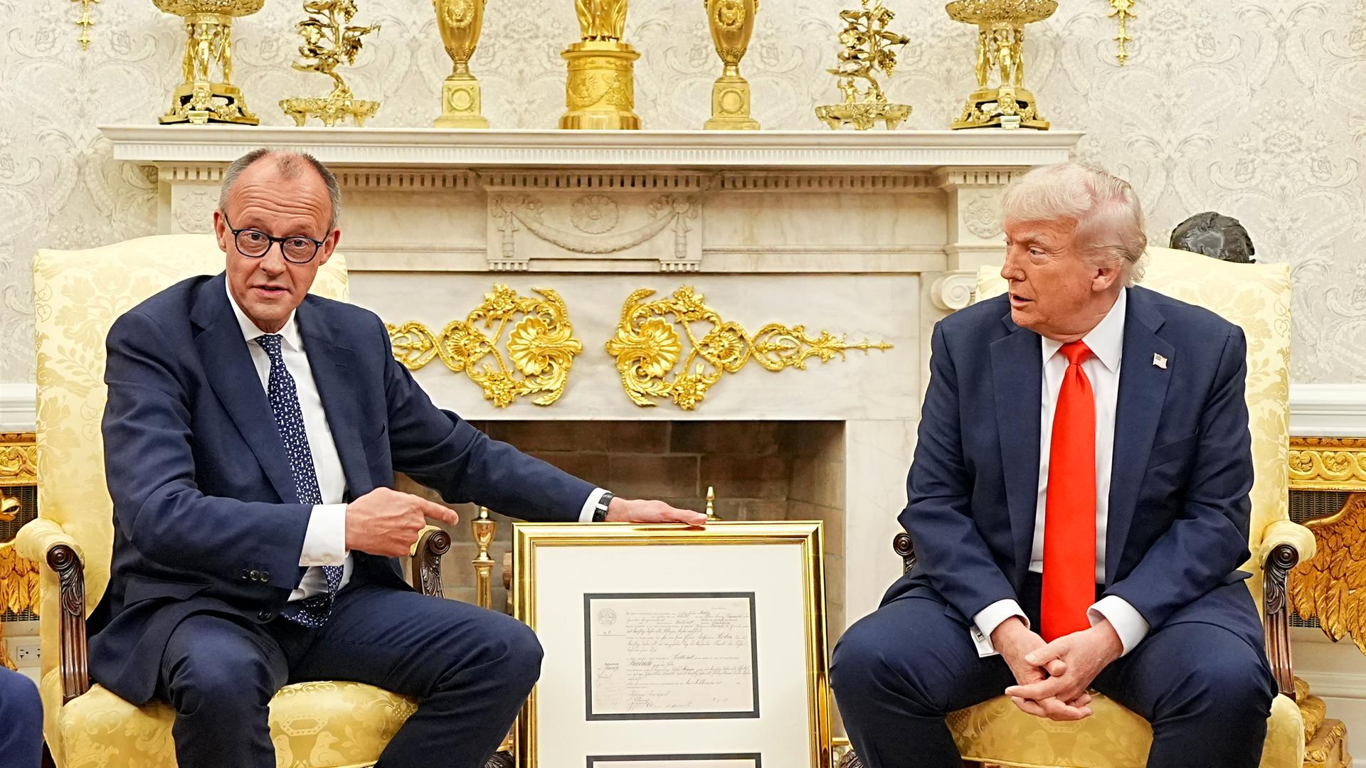 Bundeskanzler Merz und US-Präsident Trump sind vor dem Weißen Haus abgebildet.