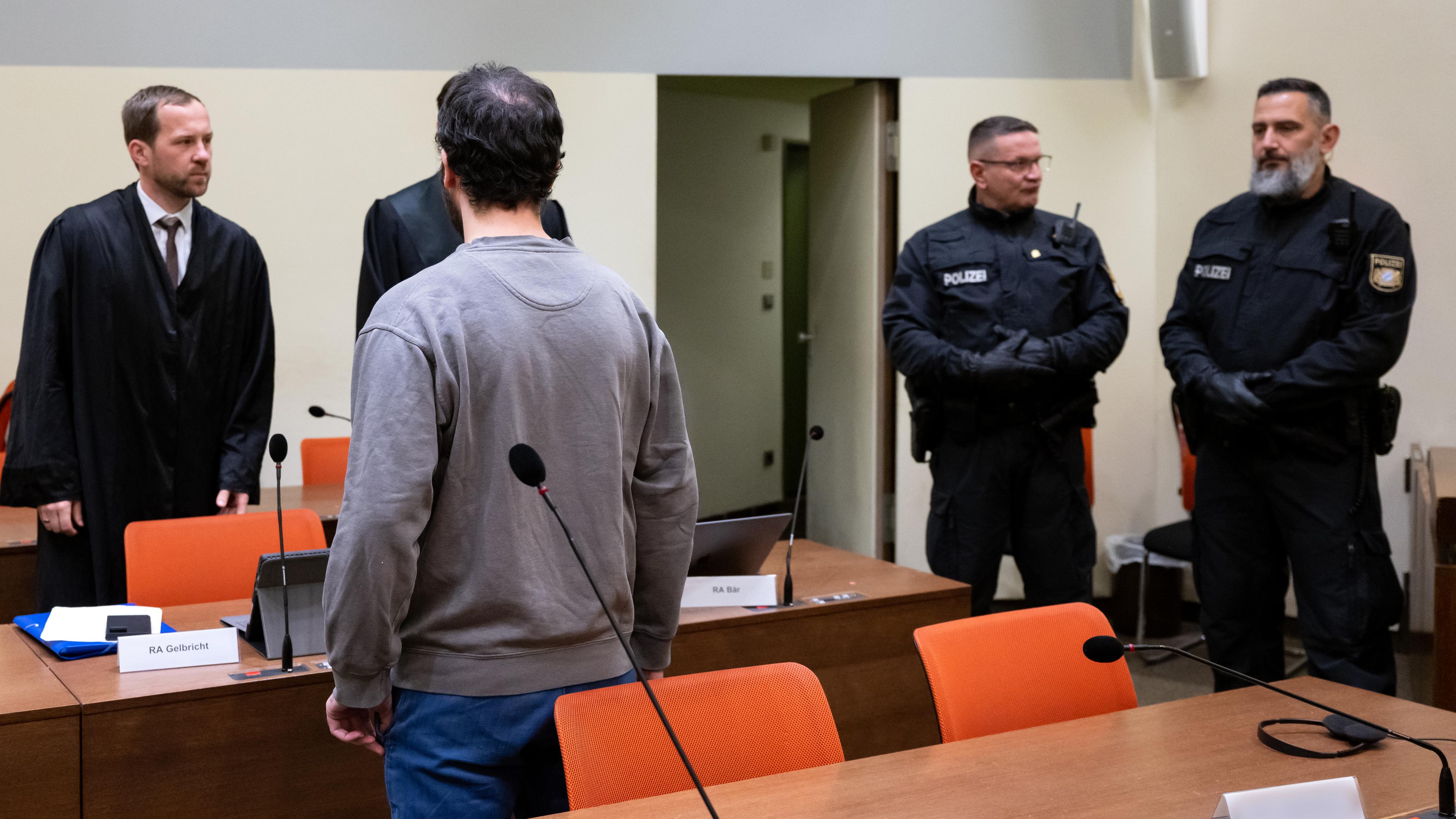 Prozess wegen Messerangriffs in ICE - Angeklagter mit Anwälten und Polizeibeamten im Landgericht München am 23.12.2022