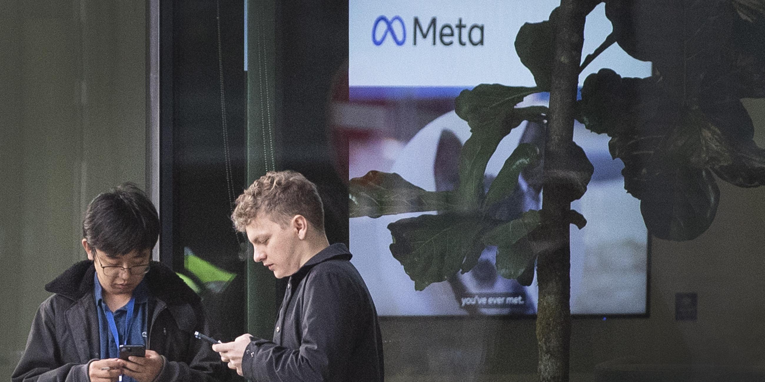 Menschen, die ihre Mobiltelefone außerhalb der Büros von Meta benutzen.