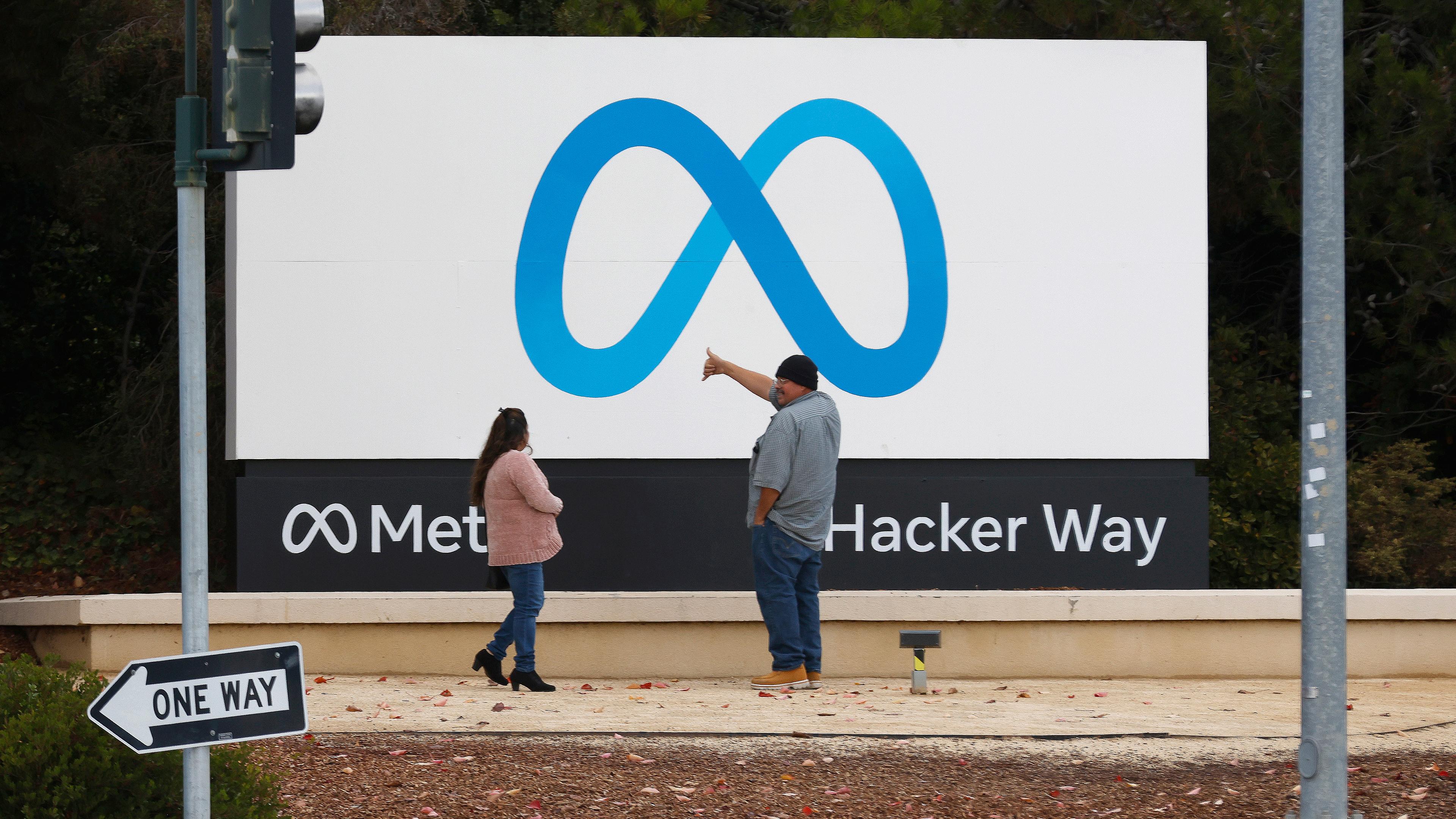 Menschen stehen vor einem Meta-Schild am Hauptsitz von Meta Platforms Inc. (ehemals Facebook, Inc.) in Menlo Park (Kalifornien, USA), aufgenommen am 08.11.2022