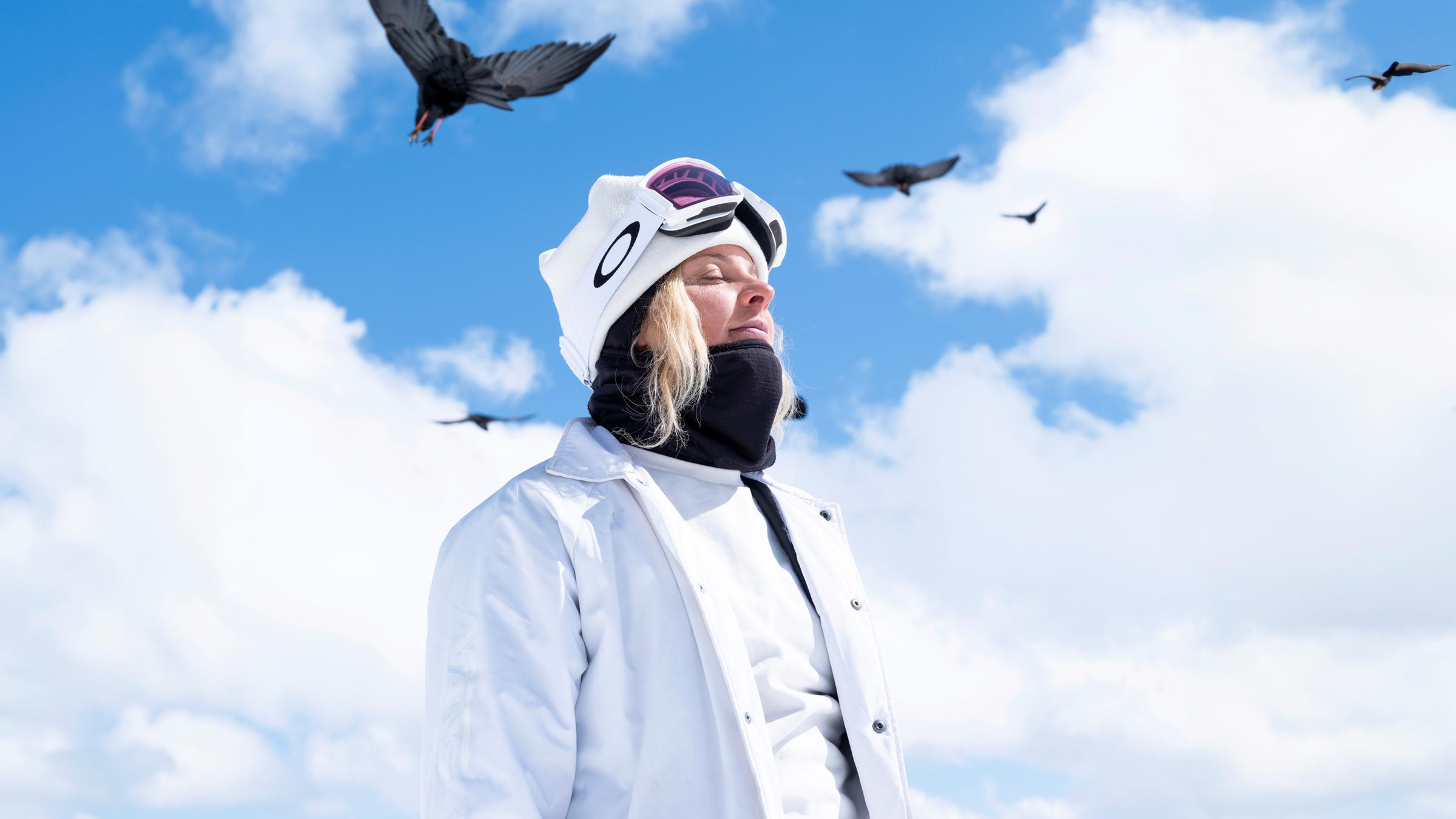Silvia Mittermüller sitzt vor einem Bergpanorama auf einem sogenannten "Jib", einem Hindernis auf einem Snowboardparcours.