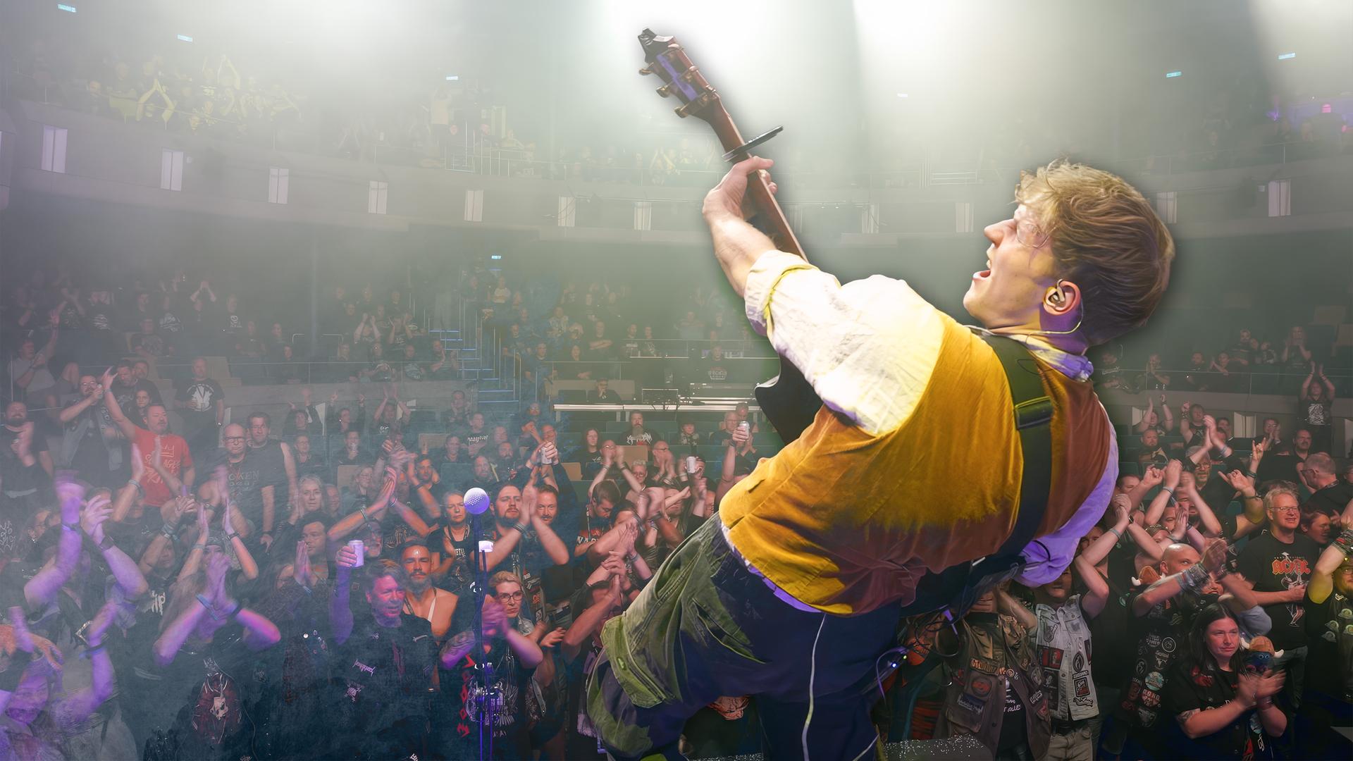 Der Gitarrist der Band "Kupfergold" steht auf der Bühne bei einem Auftritt vor Heavy Metal-Fans.