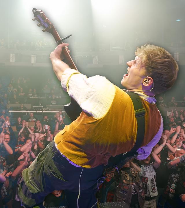 Der Gitarrist der Band "Kupfergold" steht auf der Bühne bei einem Auftritt vor Heavy Metal-Fans.