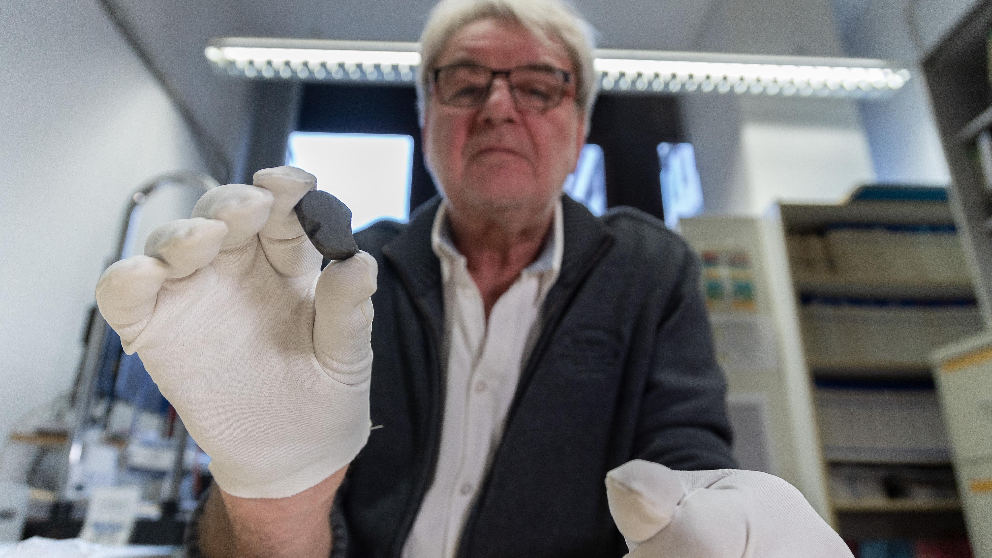 Wissenschaftler Addi Bischoff hält den Meteoriten "Flensburg" in der Hand
