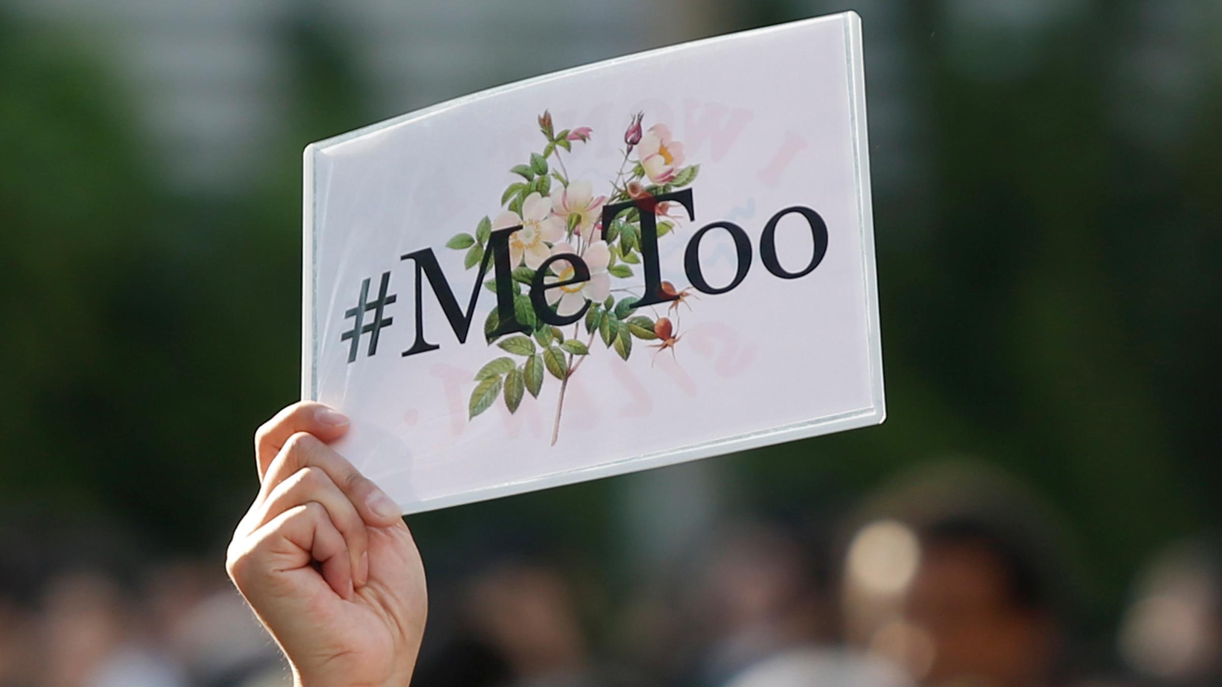 Eine Frau in Tokyo hält ein #MeToo-Protestplakat hoch.