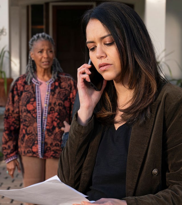 "The Rookie - Meuterei und Kopfgeld": Officer Angela Lopez (Alyssa Diaz) steht gemeinsam mit Ruth Harper (Margaret Avery) vor einem Haus. Lopez hält ein Blatt Papier in der einen, ein Smartphone in der anderen Hand. Ihr Blick ist kritisch auf das Dokument gerichtet. Ruth Harper schaut erwartungsvoll zu Lopez.