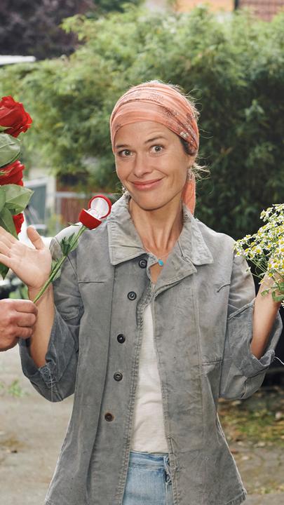 Anna (Meike Droste) steht zwischen Albert (Oliver Stokowski) und Robert (Stephan Luca) und hält ratlos die Hände in die Luft. Sie blickt gequält lächelnd in die Kamera. Albert und Robert sehen sich feindselig an, beide halten einen Blumenstrauß in den Händen, Albert hält eine Flasche Sekt und präsentiert einen Verlobungsring.