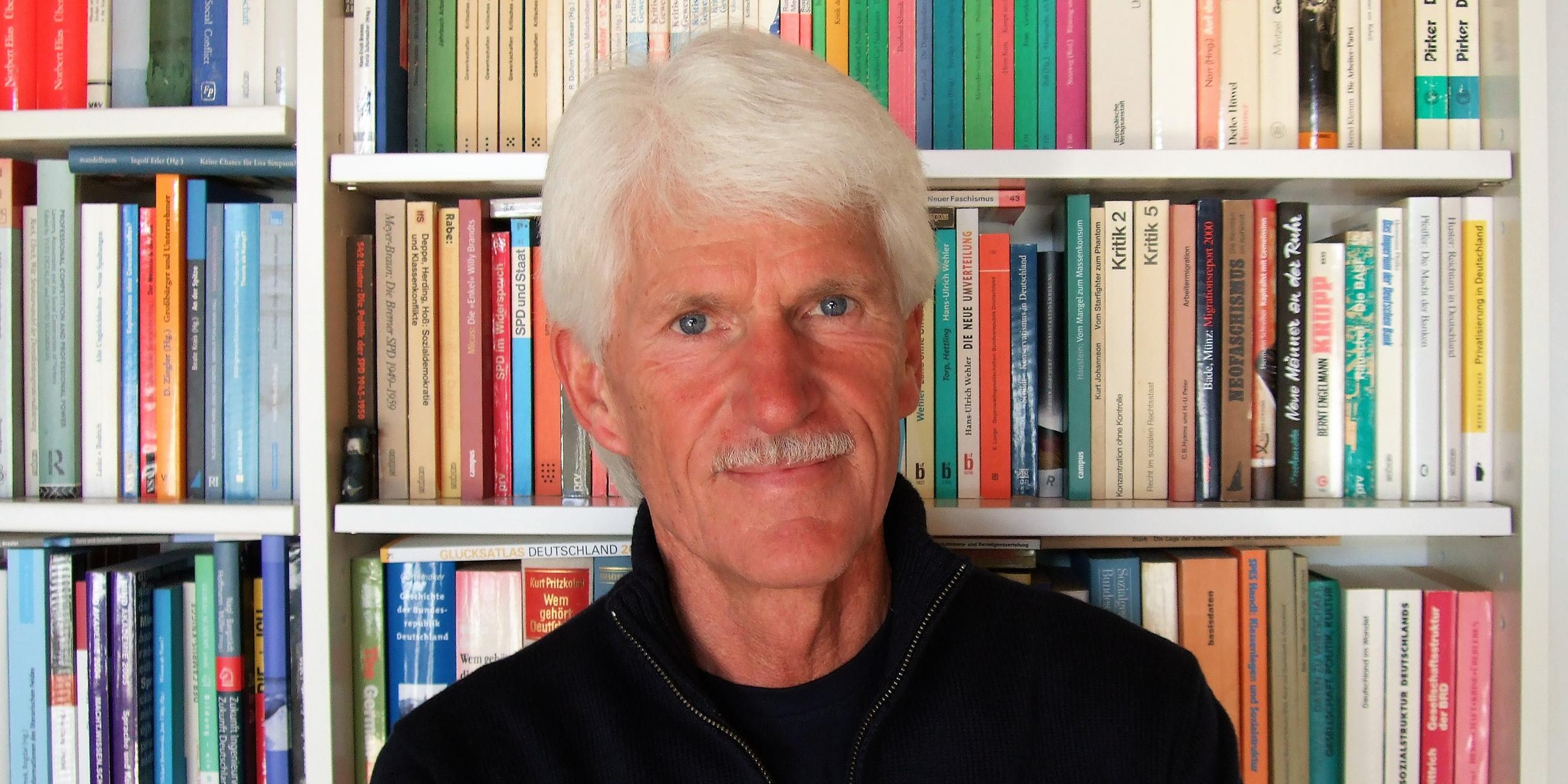 Der Soziologe Michael Hartmann vor einem Bücherregal.