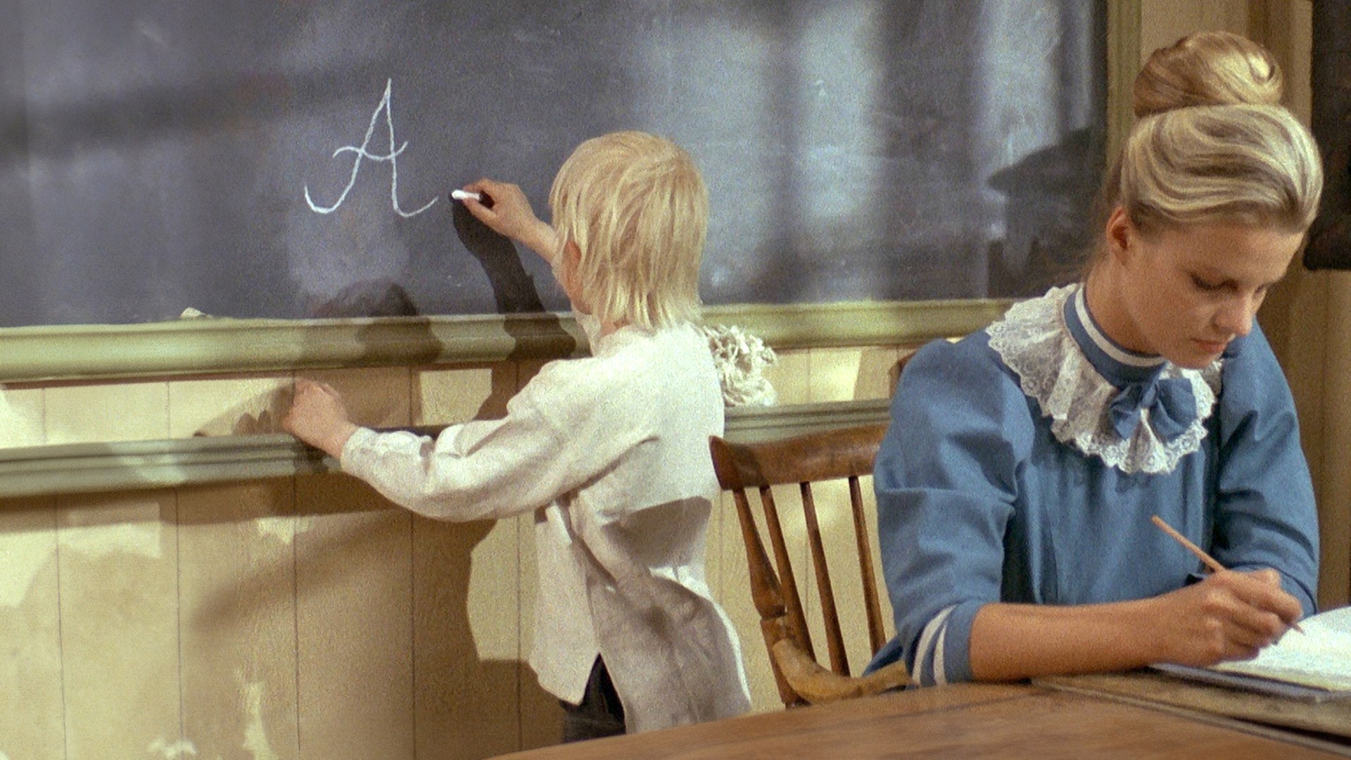 In der Schule steht Michel an der Tafel mit dem Rücken zur Lehrerin.
