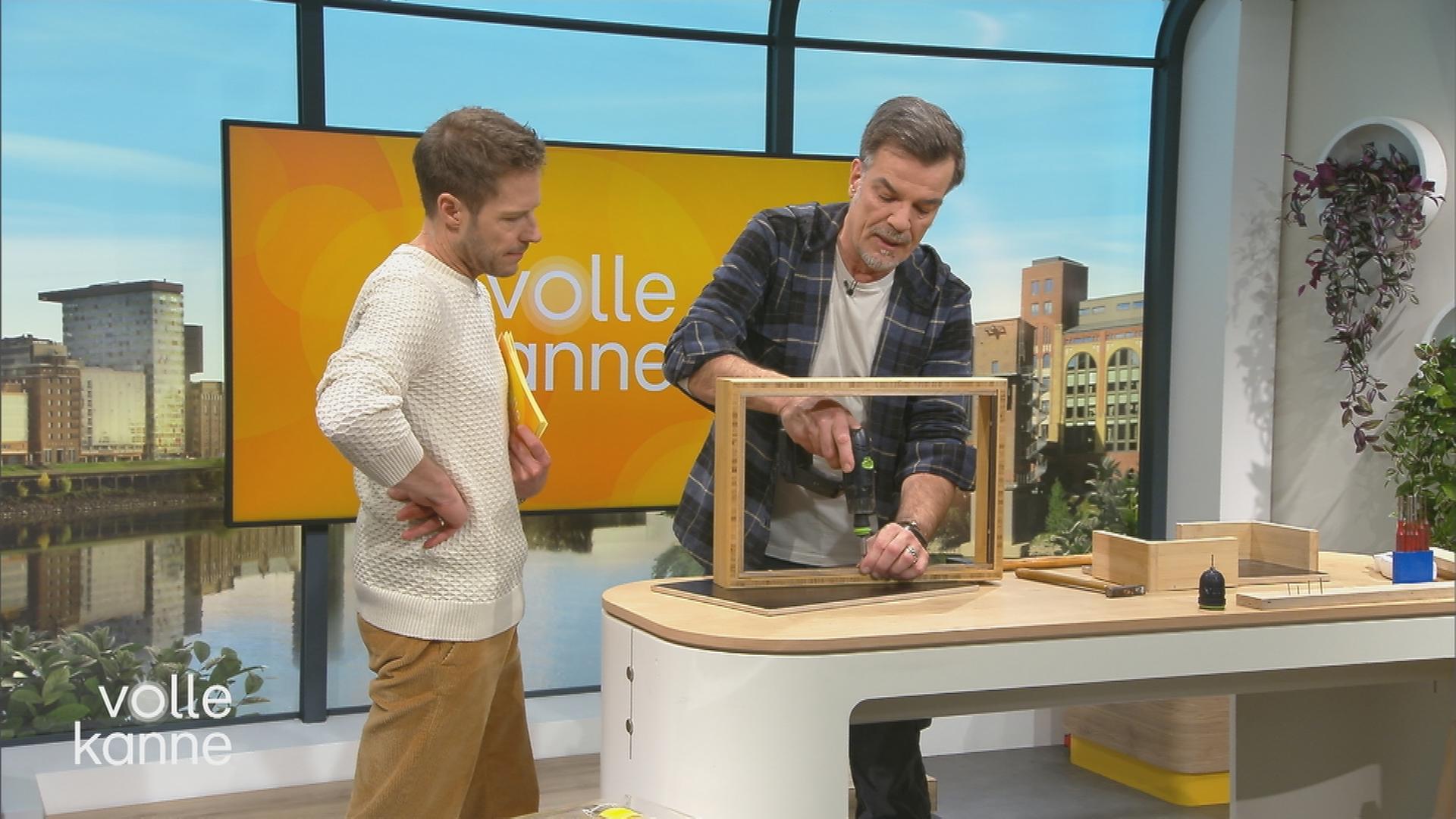 Mick Wewers bohrt in eine Regalwand. Florian Weiss schaut zu.