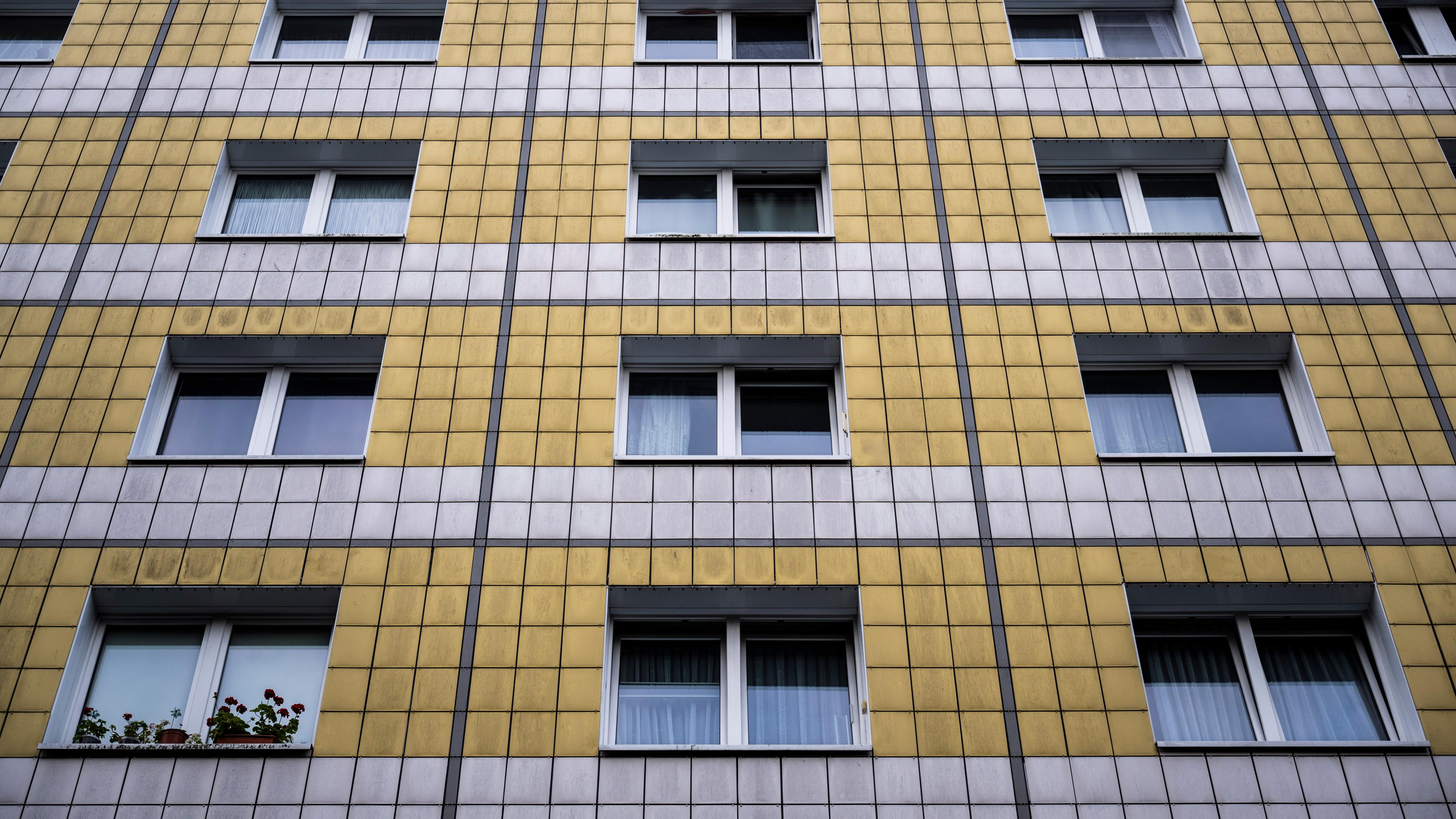 An einer gelb-weißen Hausfassade sind Fenster wie ein Muster angeordnet.