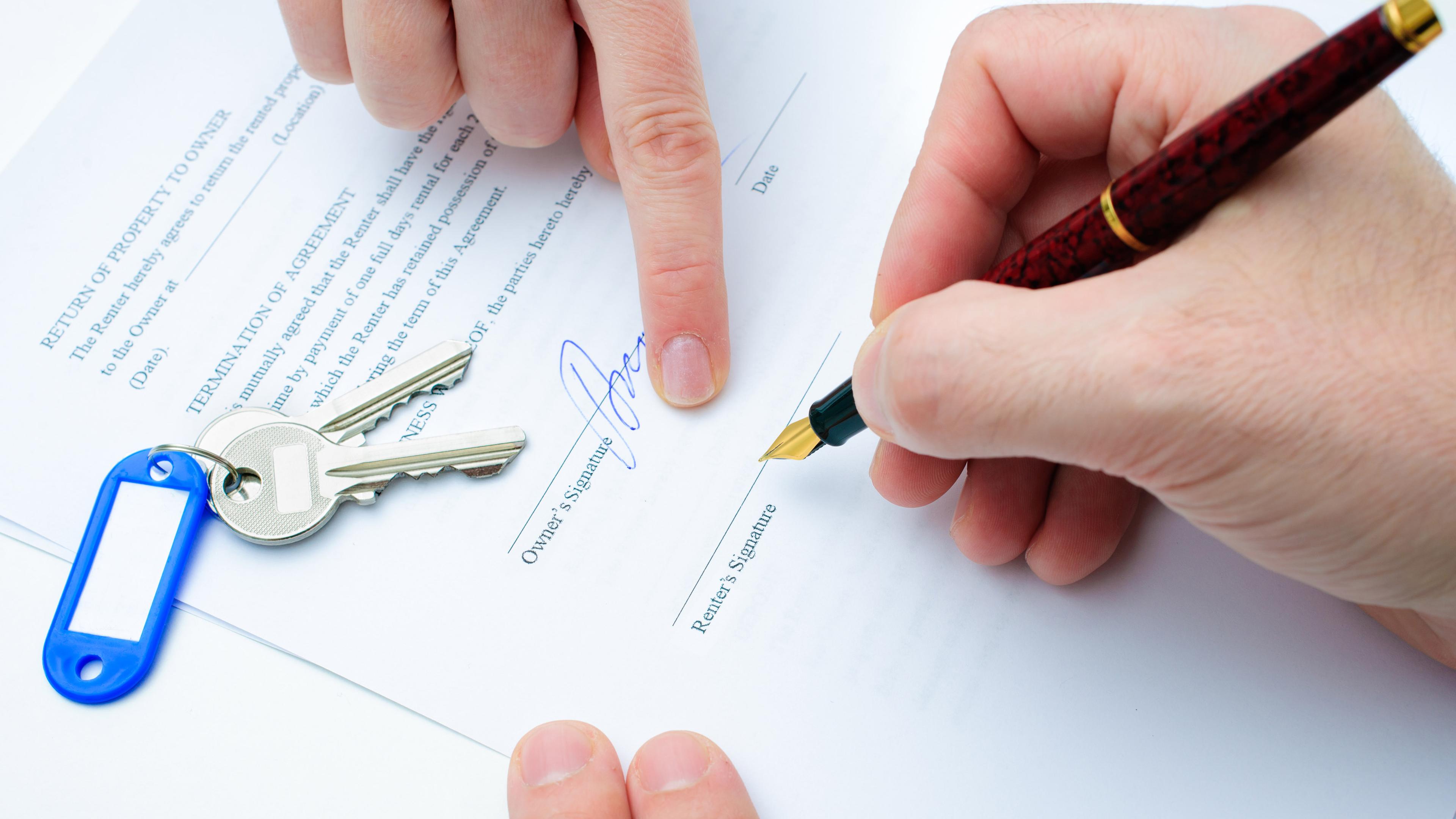 Eine Person unterschreibt einen Mietvertrag.
