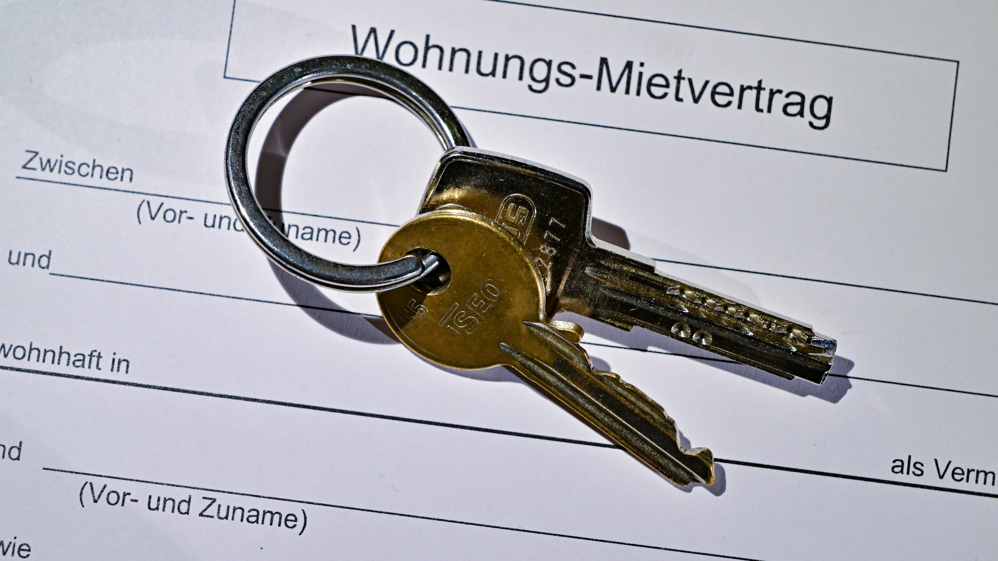 Ein Wohnungsschlüssel liegt auf einem Mietvertrag für eine Wohnung. 