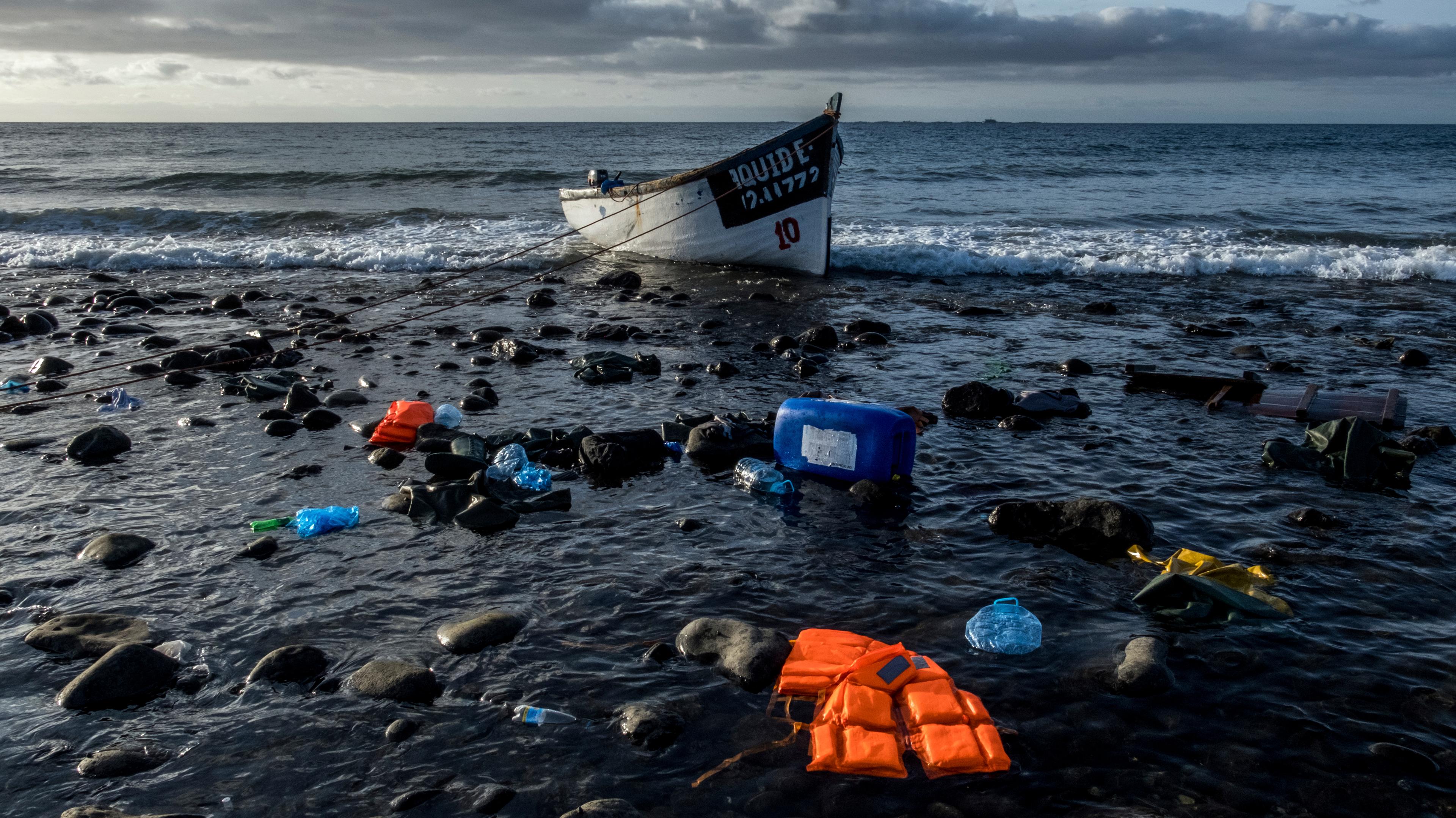Ein Boot liegt neben Schwimmwesten und Müll am Strand (Symbolbild Flucht über das Meer).