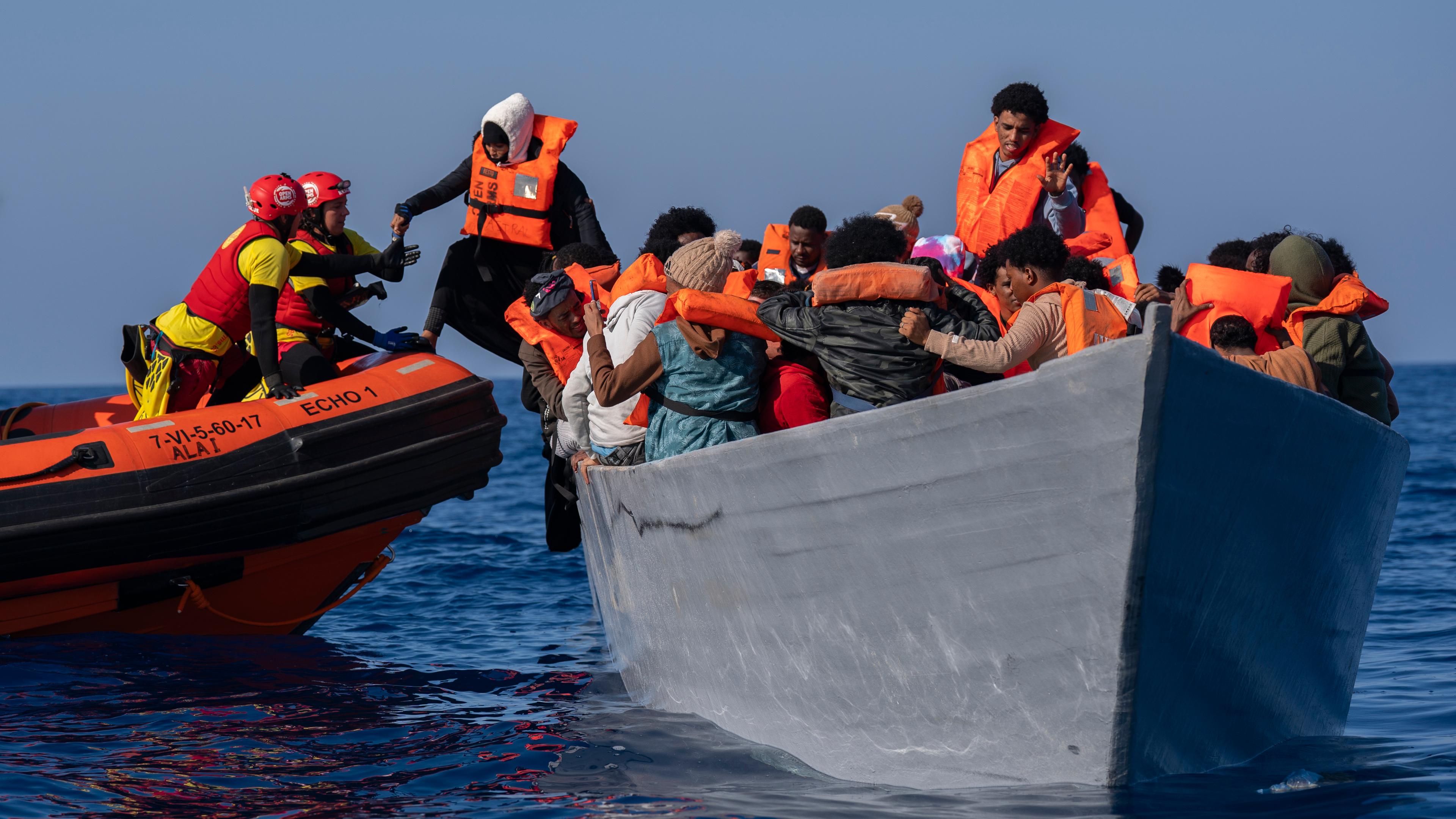 Migranten drängen sich an Deck eines Holzbootes, während sie von Helfern der spanischen Nichtregierungsorganisation Open Arms auf dem Mittelmeer, etwa 30 Meilen nördlich von Libyen, unterstützt werden