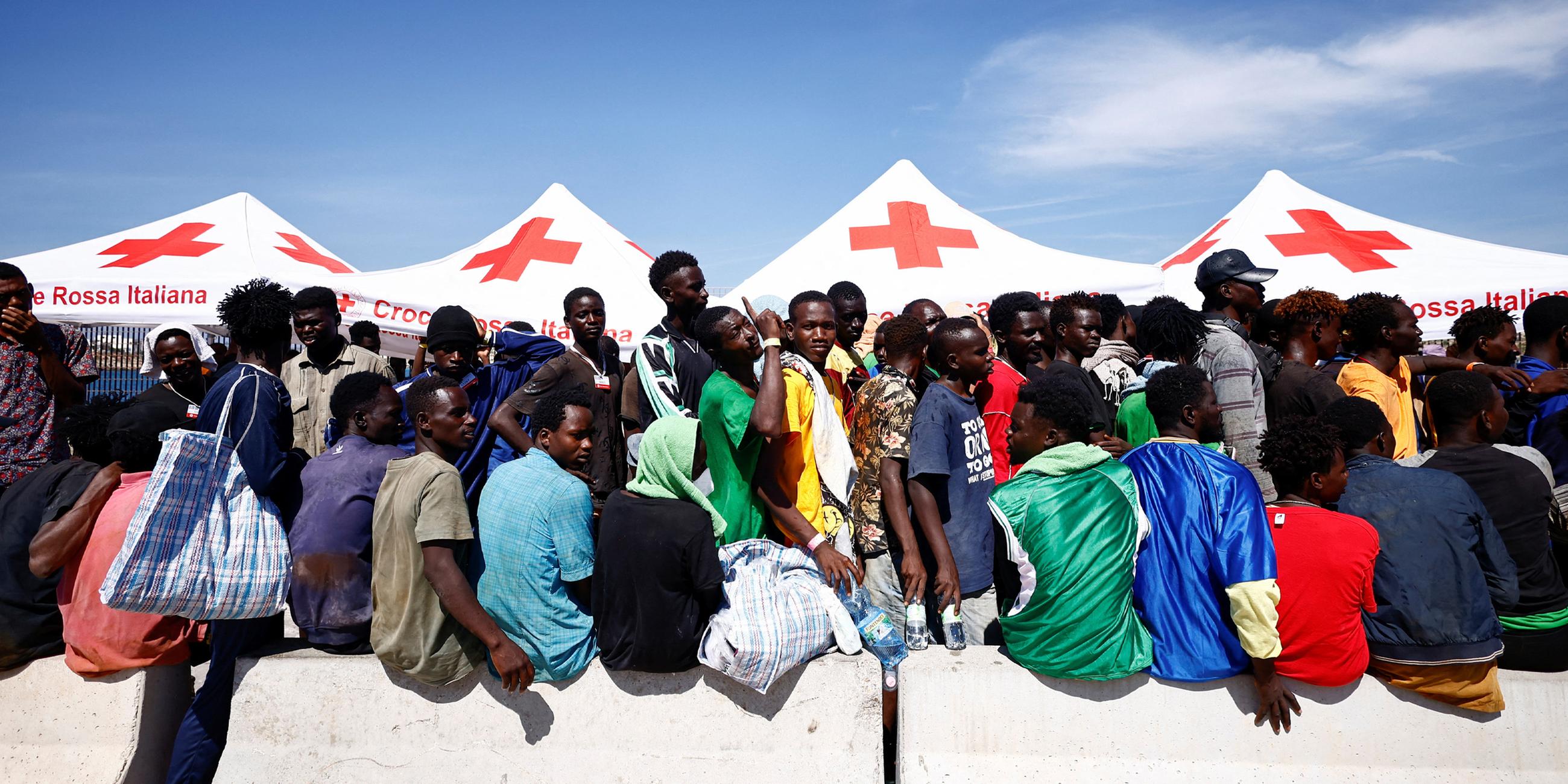 Migranten warten am Hafen auf der sizilianischen Insel Lampedusa am 14.09.2023 auf ihre Überführung auf das Festland. 