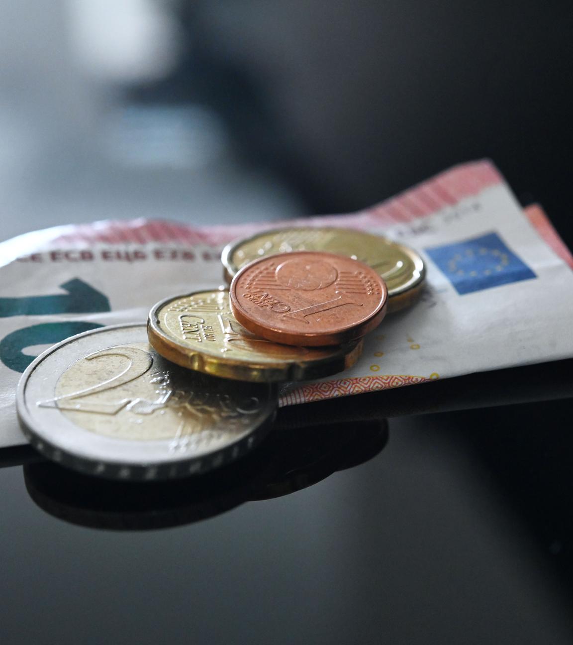 Münzen und ein Geldschein im Wert von insgesamt 12,41 Euro liegen auf einer schwarzen Fläche.