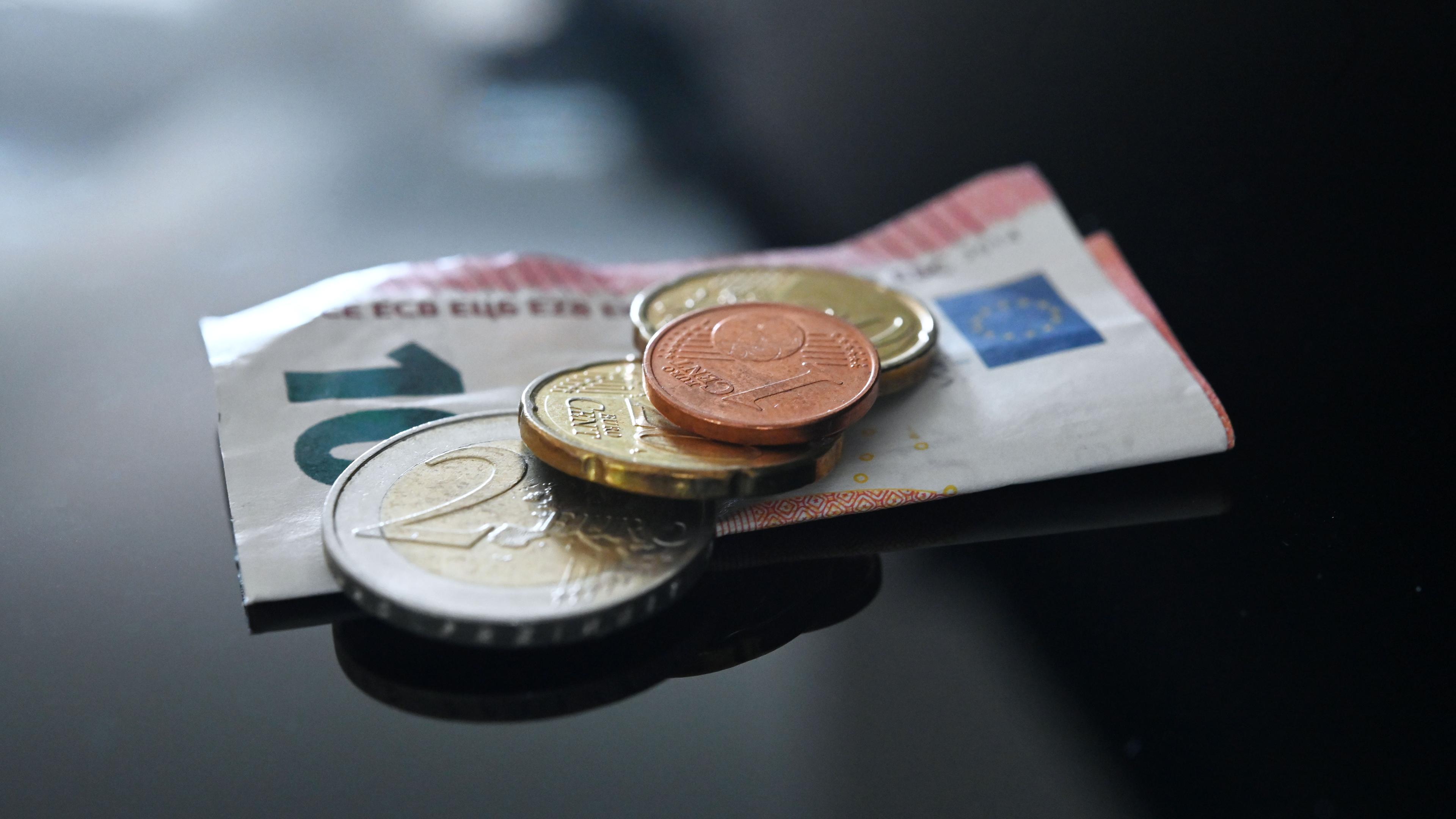 Münzen und ein Geldschein im Wert von insgesamt 12,41 Euro liegen auf einer schwarzen Fläche.