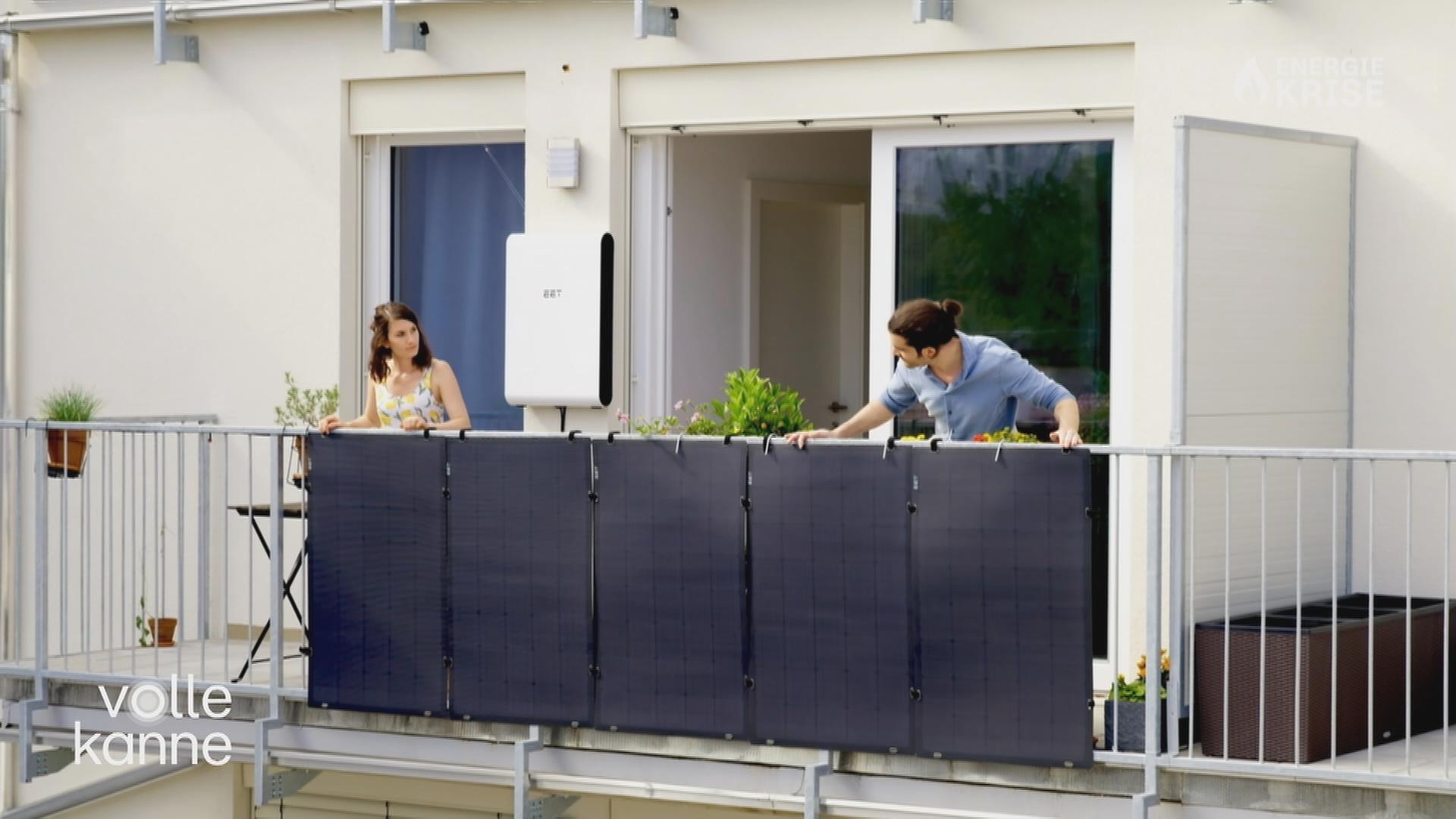 Zwei Frauen stehen auf einem Balkon, an dessen Geländer eine Photovoltaik-Anlage befestigt ist