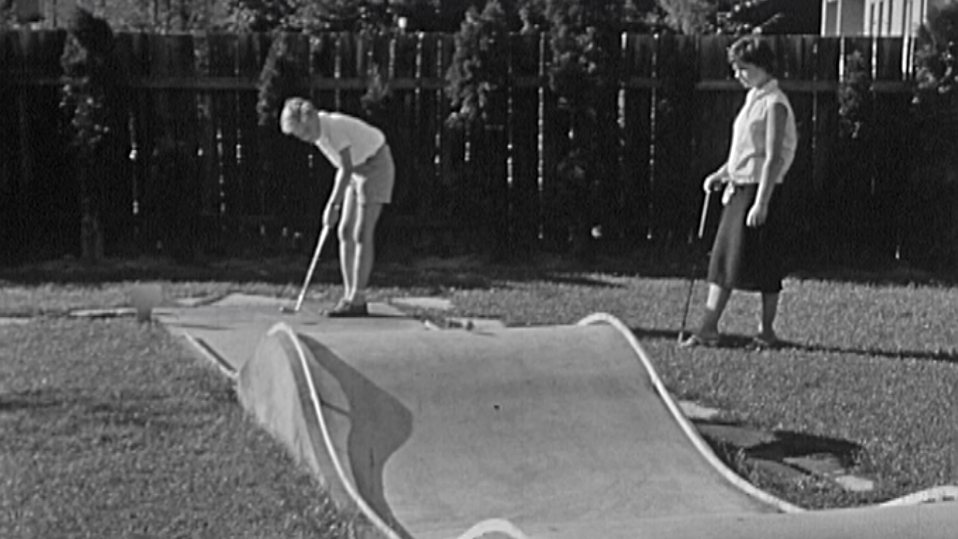 Ein schwarz-weiß Bild von zwei Frauen, die Minigolf spielen