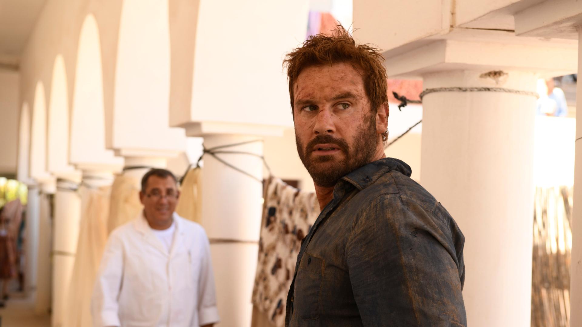 "Mirage - Gefährliche Lügen": Auf einem orientalischen Markt. Gabriels (Clive Standen) Gesicht und Hemd sind schmutzig - er schaut gehetzt über seine Schulter nach hinten.