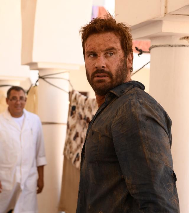 "Mirage - Gefährliche Lügen": Auf einem orientalischen Markt. Gabriels (Clive Standen) Gesicht und Hemd sind schmutzig - er schaut gehetzt über seine Schulter nach hinten.