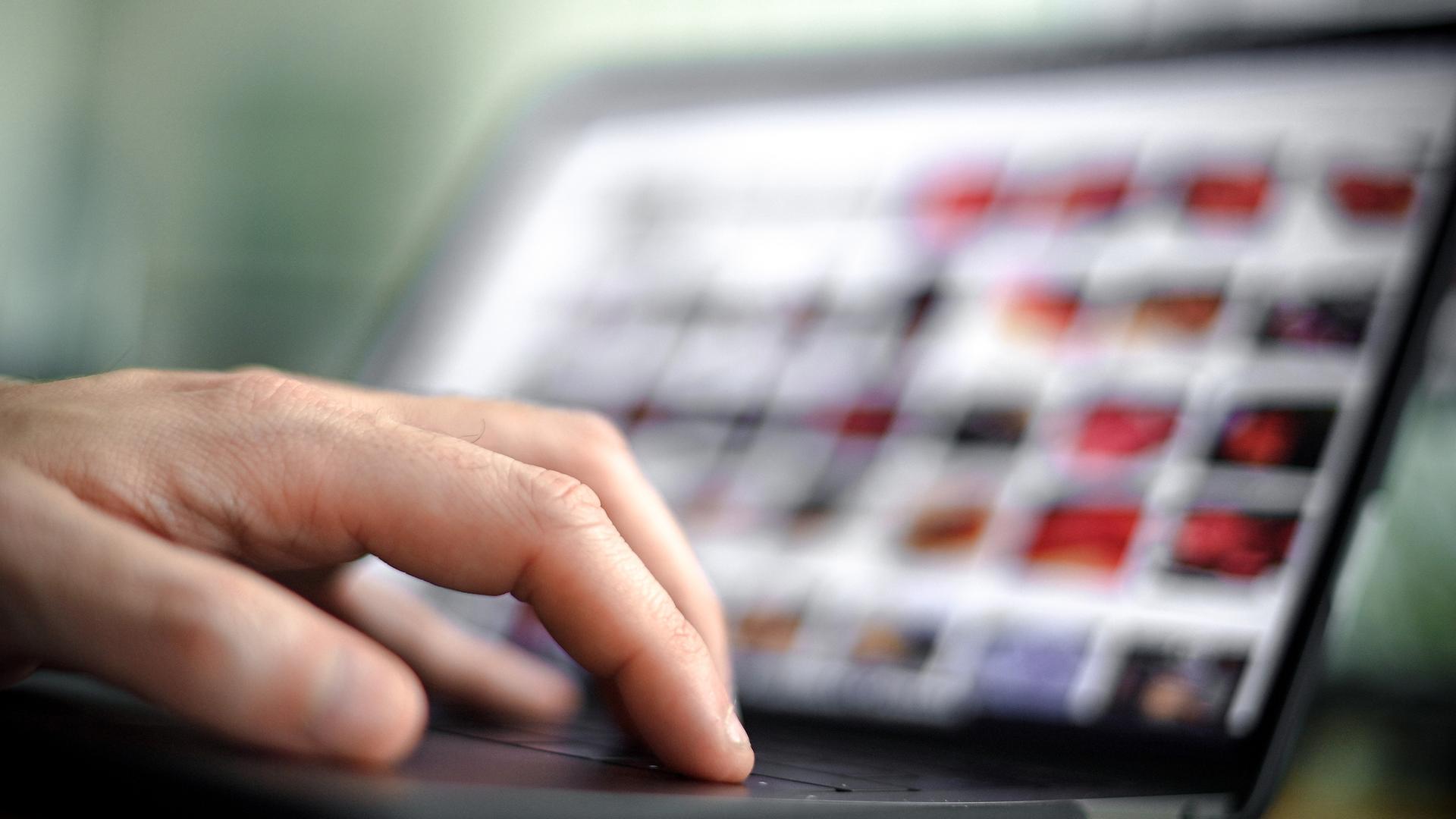 Die Finger einer Hand auf dem Tastatur eines geöffneten Laptops.