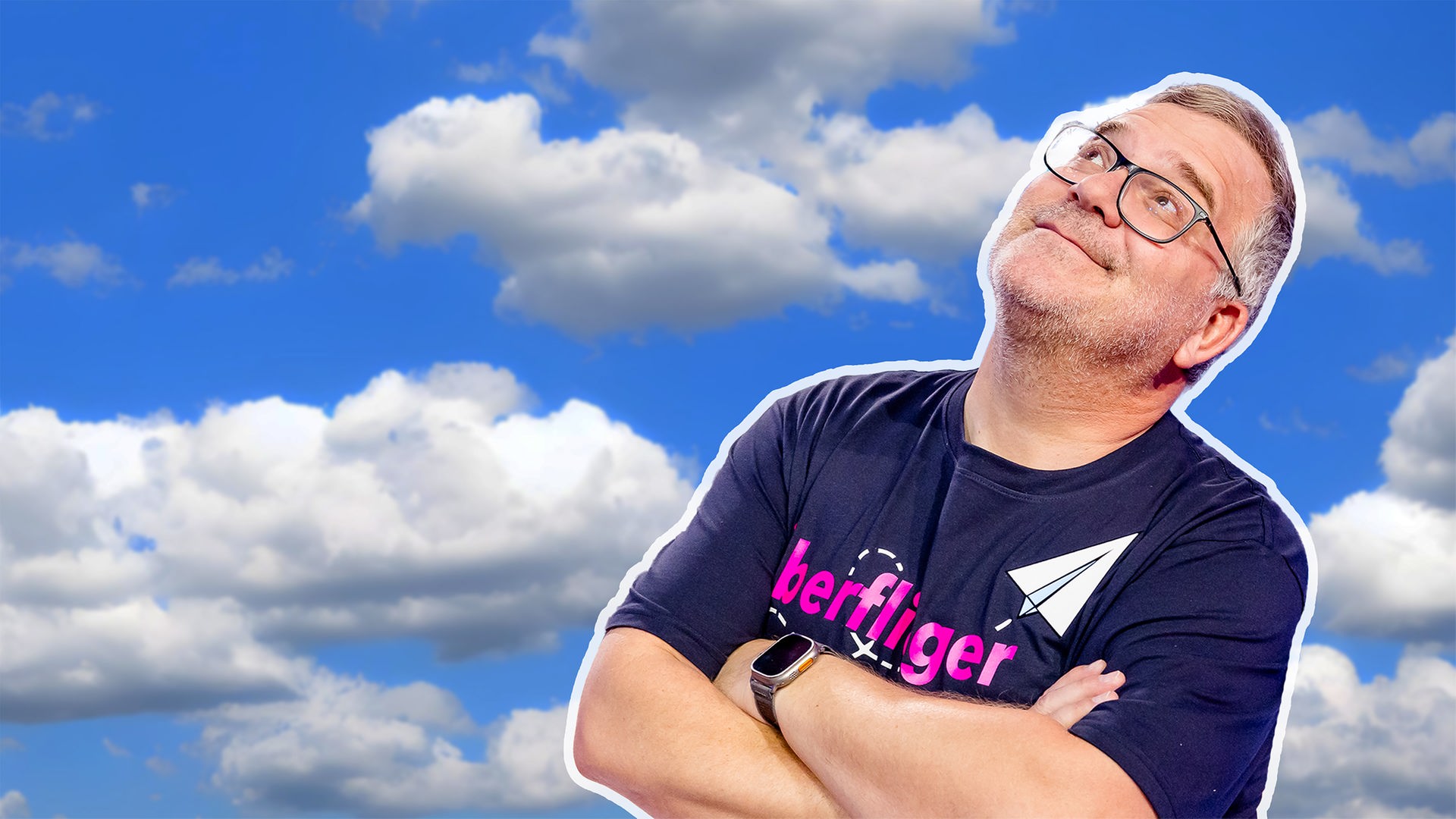 Elton steht vor einem blauen Himmel mit Wolken, die Arme verschränkt. Er blickt leicht lächelnd nach oben.