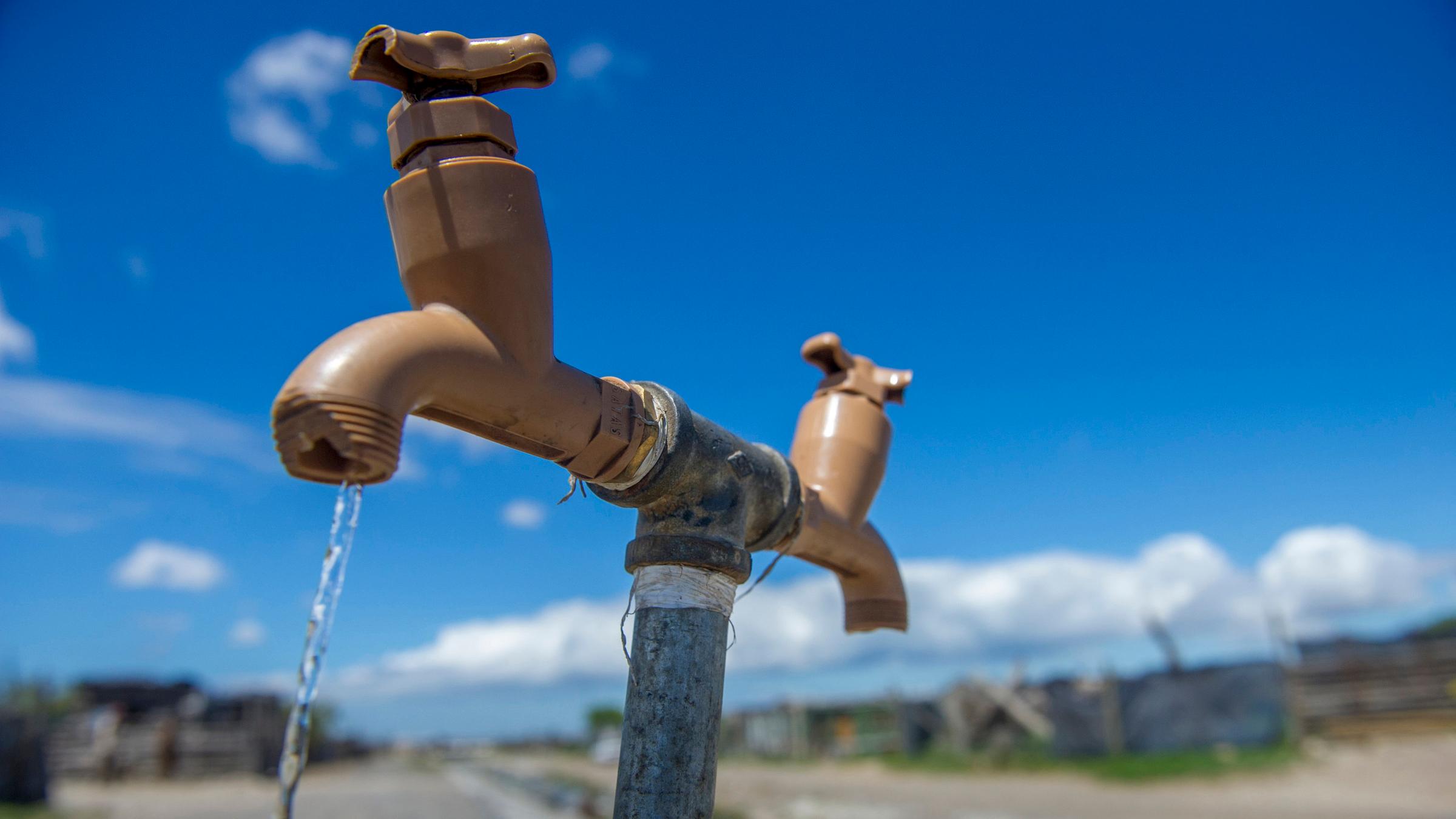 "Mission Trinkwasser - Wie stillen wir den Durst der Menschheit?": Symbolbild für Wasserknappheit: Wasserhahn im Feld. Trinkwasser fließt. 
